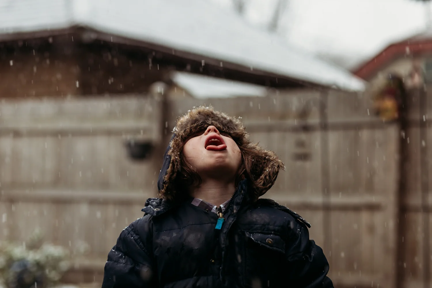 My son catching falling snow flakes. See the neighbor's garage?