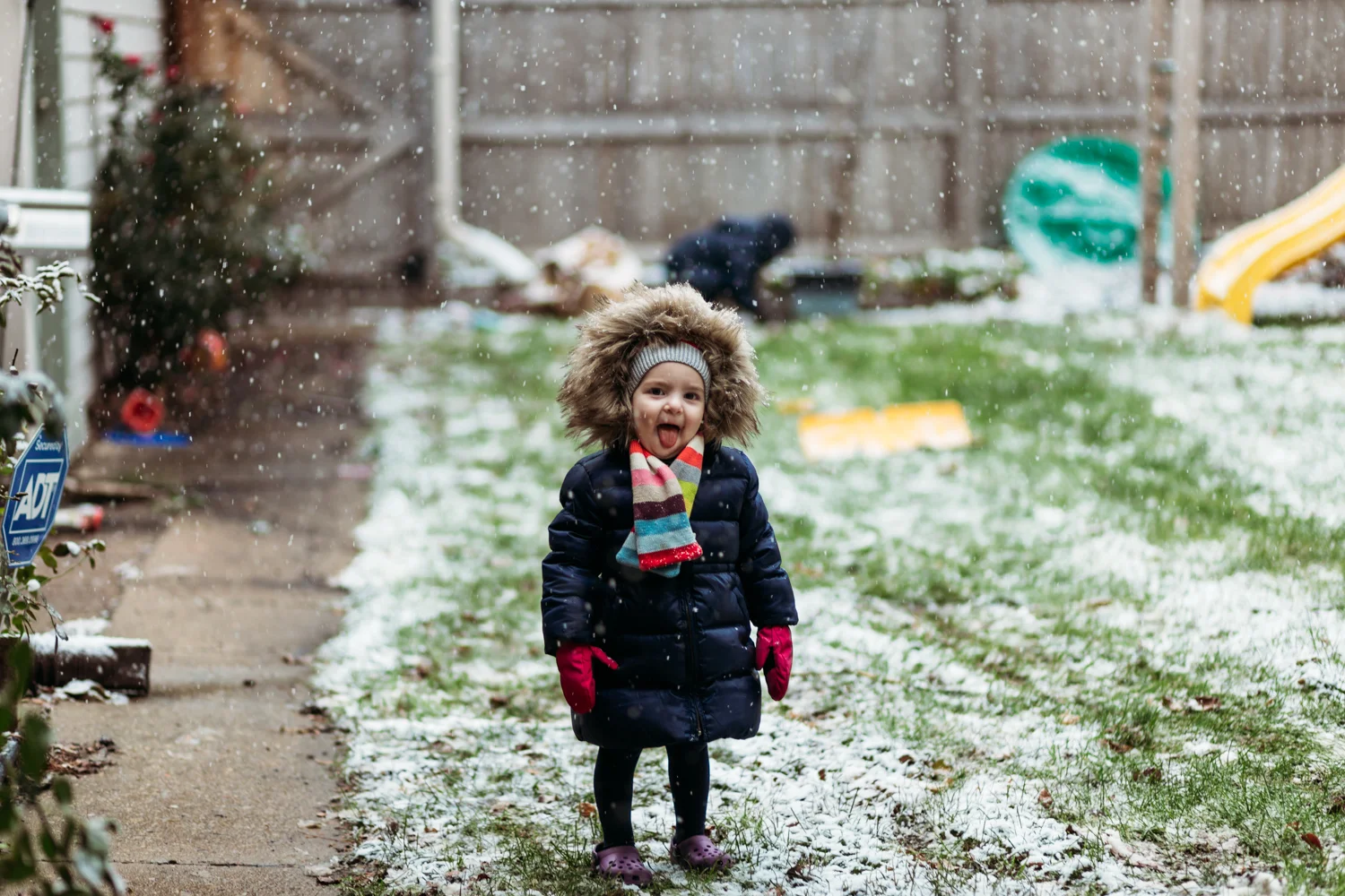 Little girl catching falling snow with her tongue.