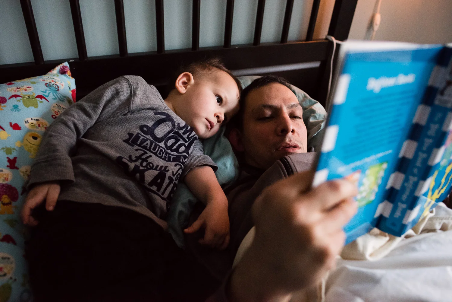 Alexandria Virginia family lifestyle and documentary photography, father and son snuggle while reading in bed