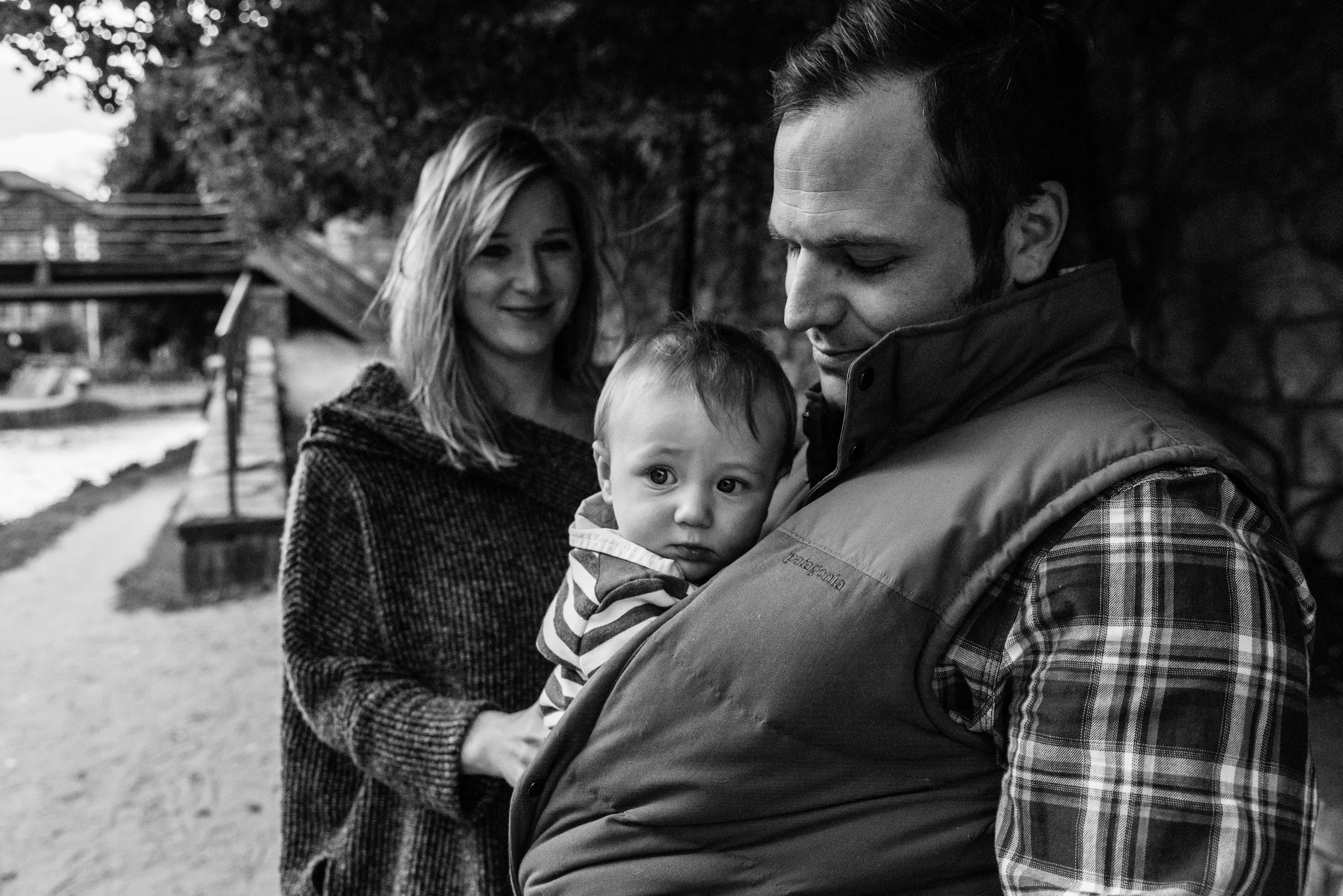 Mom snuggling baby with Dad watching | Nicole Sanchez Family Documentary Photographer