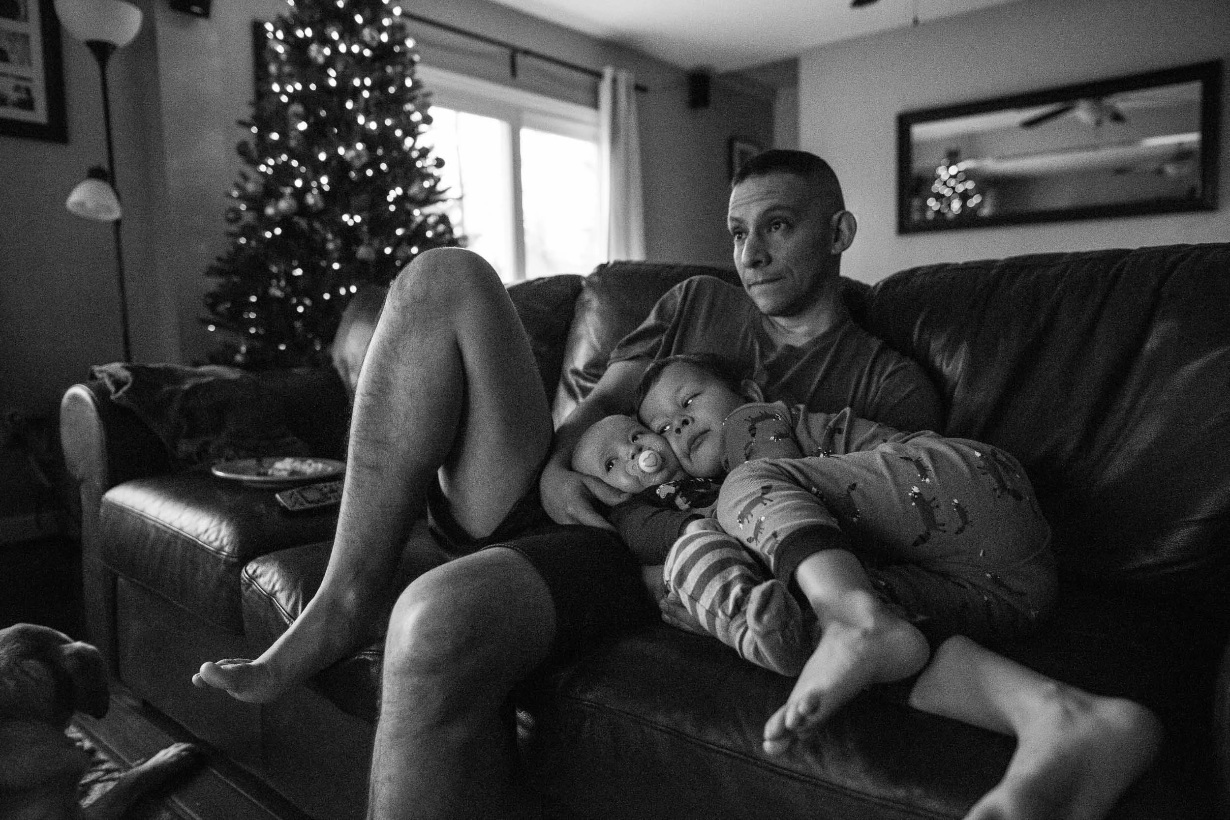 father and two boys laying together on couch by Northern Virginia Lifestyle photographer Nicole Sanchez