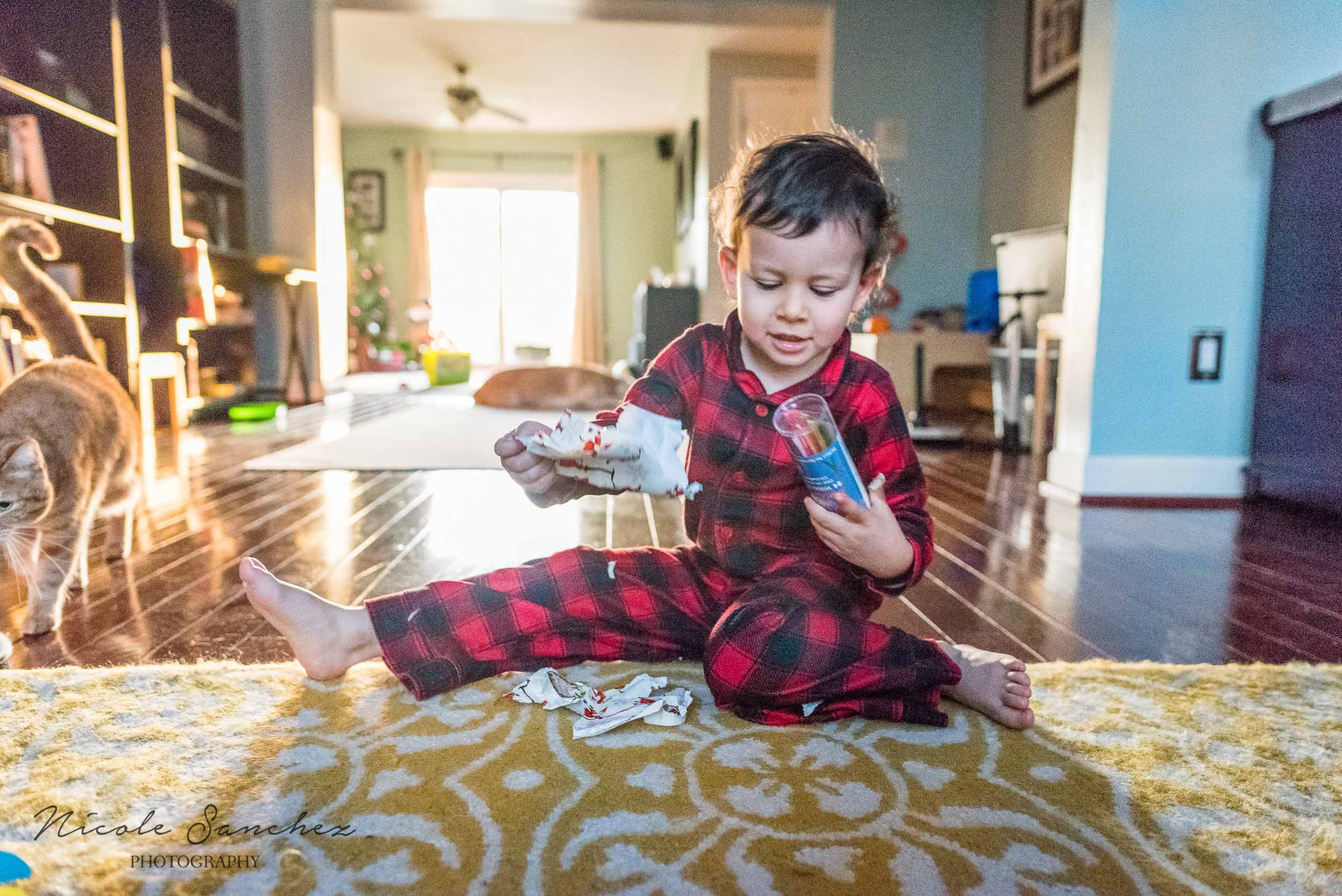 Boy opening present on Christmas morning by Alexandria, VA Lifestyle Family Photographer Nicole Sanchez