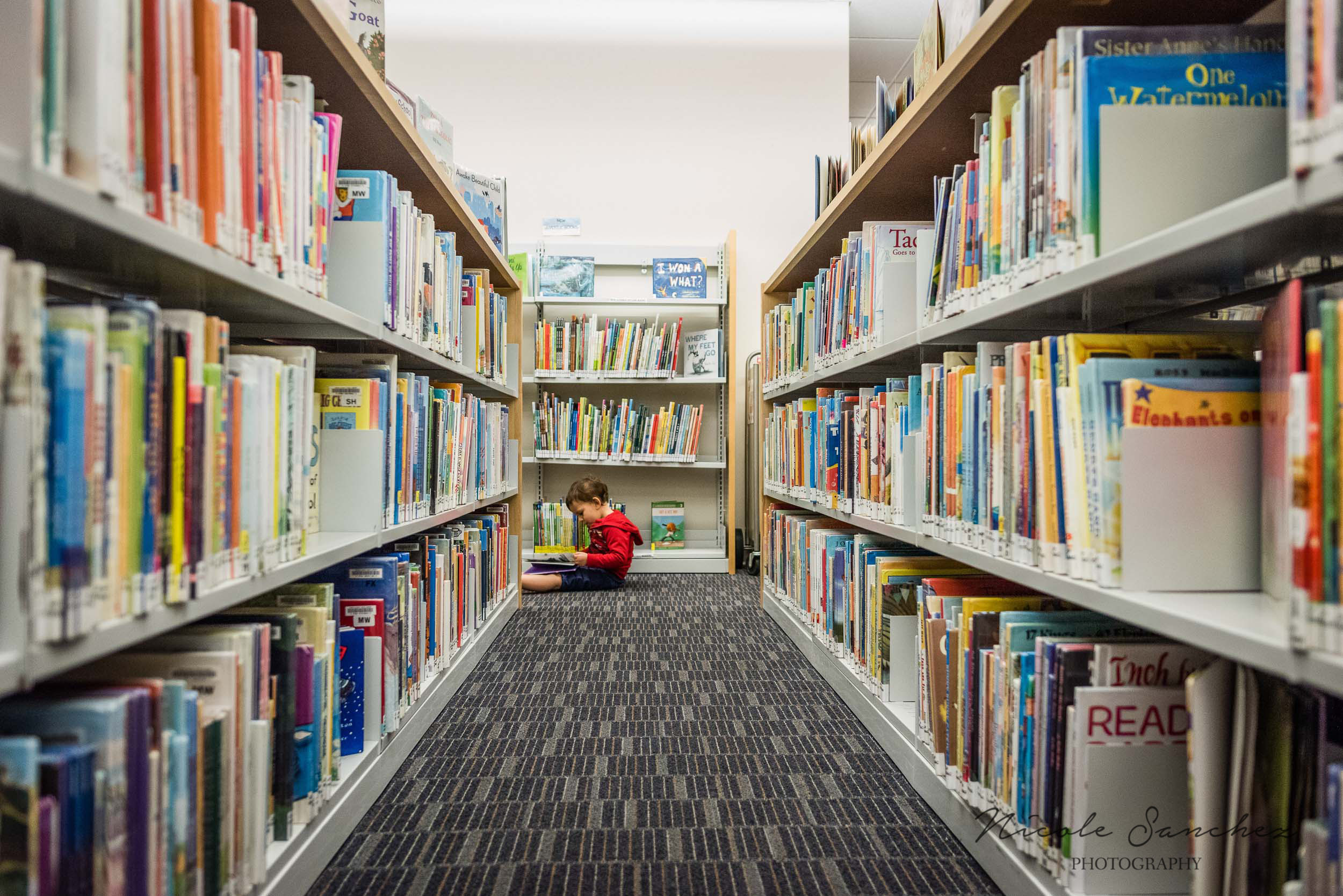 Boy reading in floor at Alexandria, VA Library by Nicole Sanchez Photographer