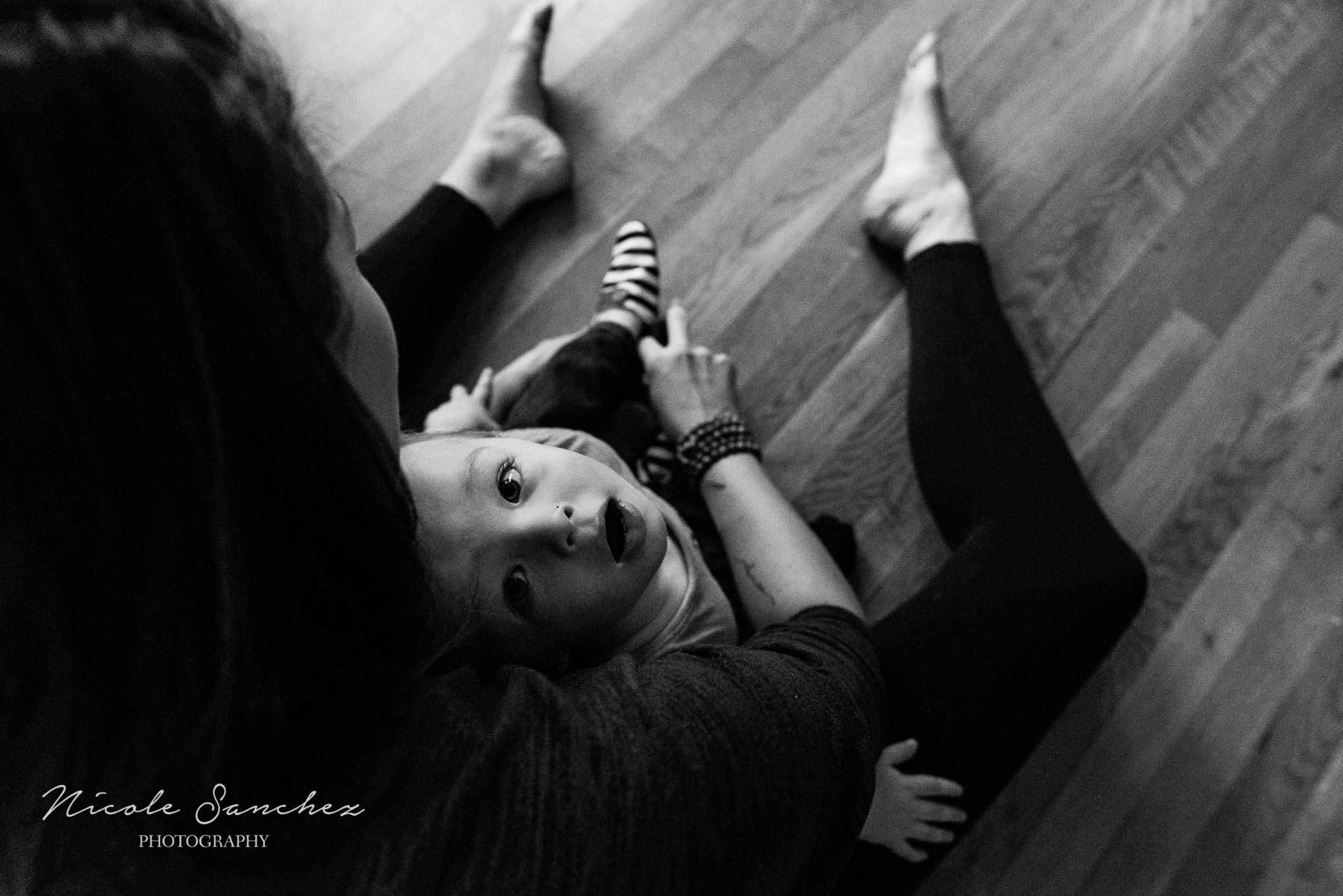 Boy looking up as mom puts on his shoes by Alexandria, VA Family Photographer Nicole Sanchez