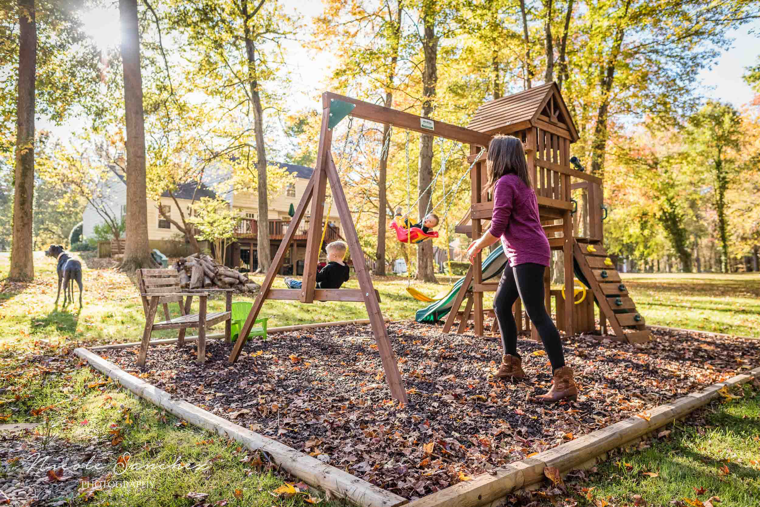 Mom pushing two sons in swings in backyard playground in Northern Virginia by Family Photographer Nicole Sanchez