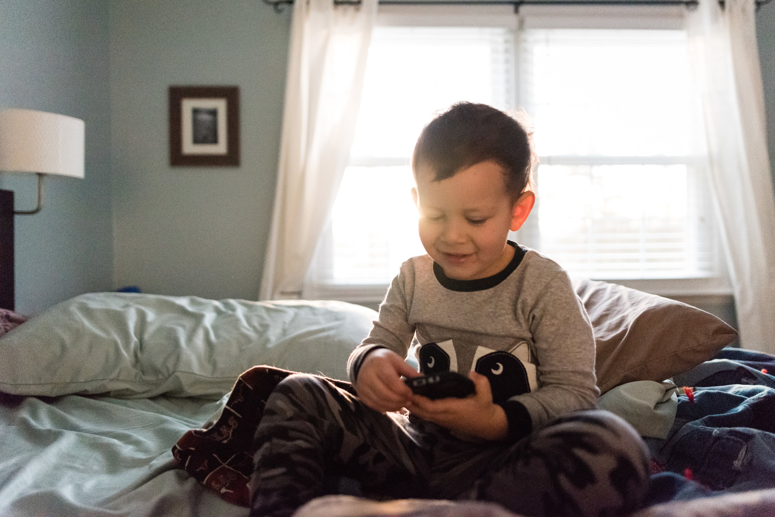 Boy texting on bed by Alexandria, VA Family Photographer Nicole Sanchez