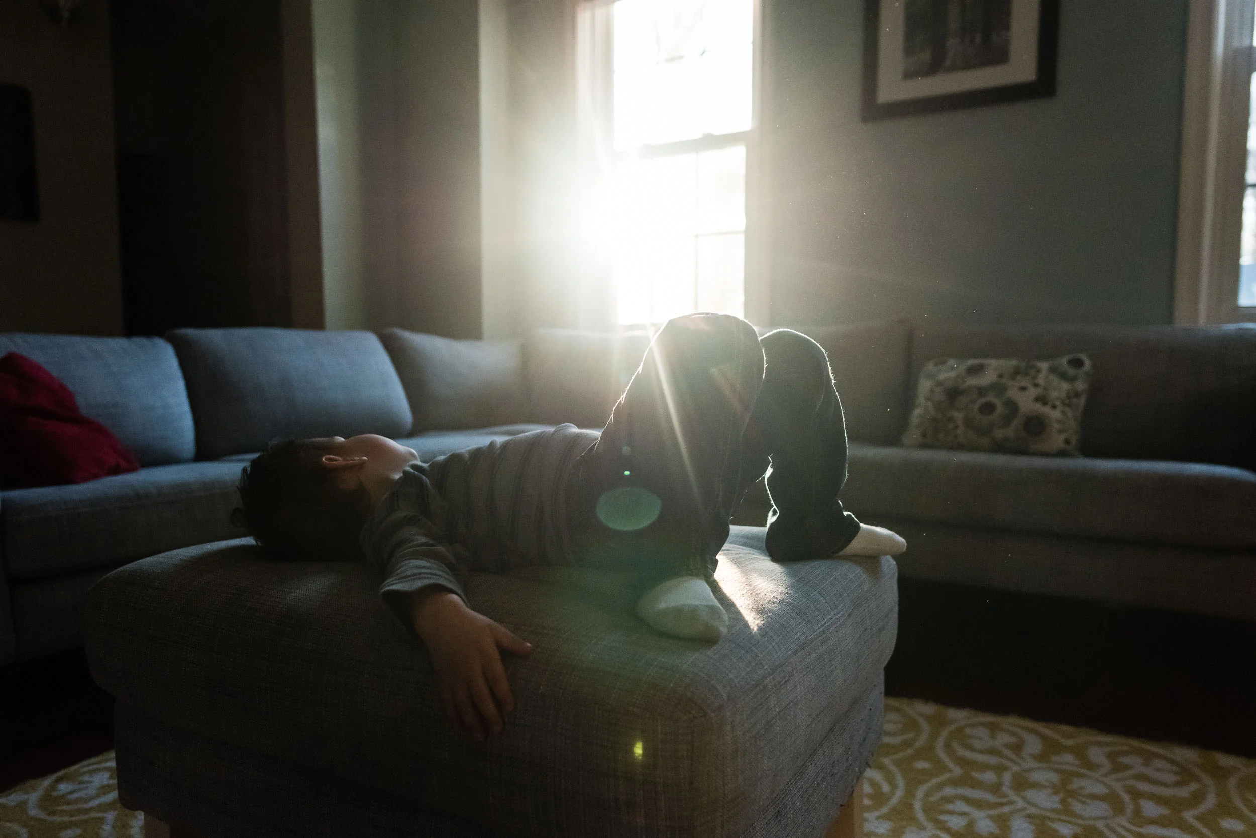 Boy resting on ottoman with sun flare by Northern Virginia Family Photographer Nicole Sanchez