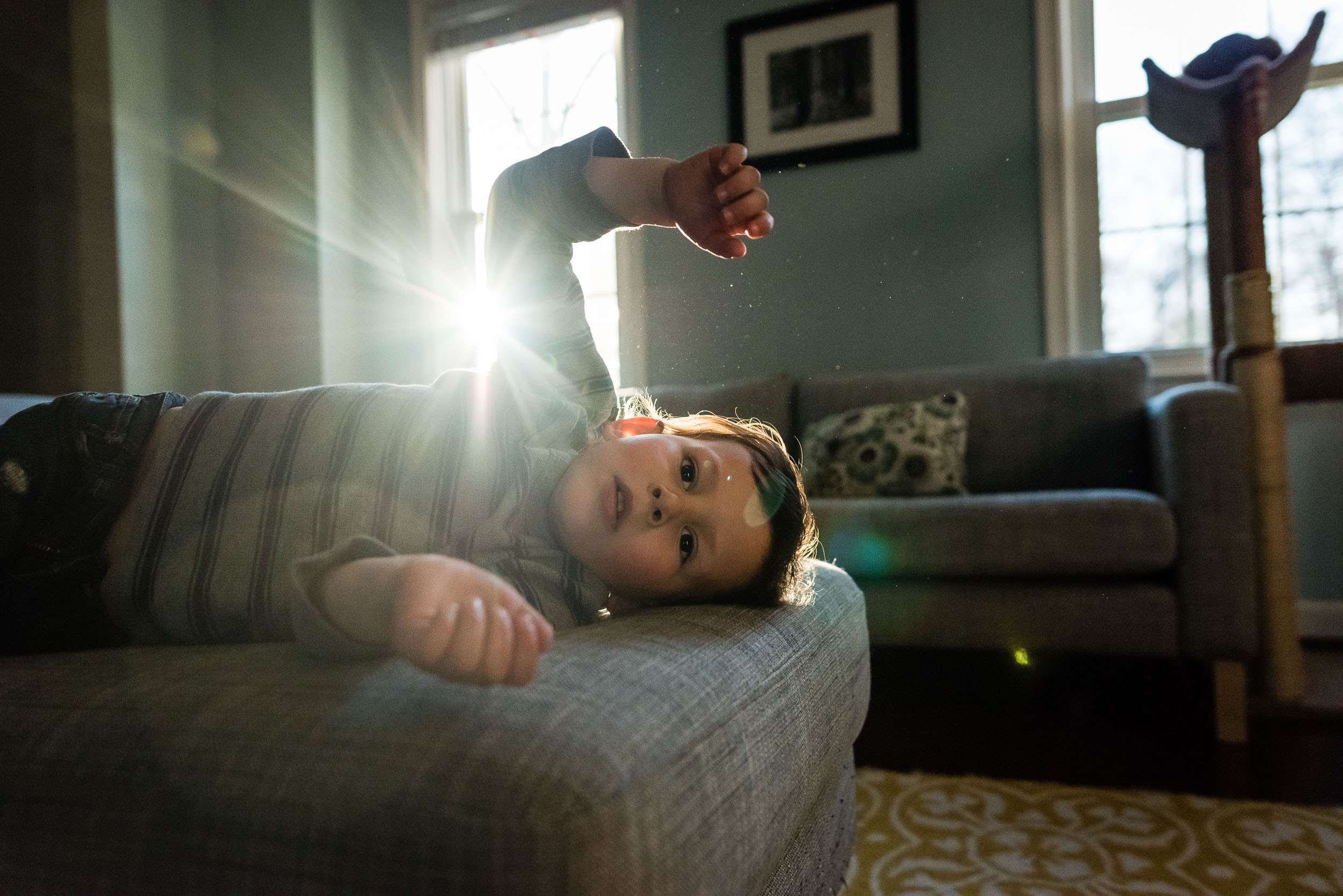 Boy resting on couch with Sun flare by Alexandria, VA Family Photographer Nicole Sanchez
