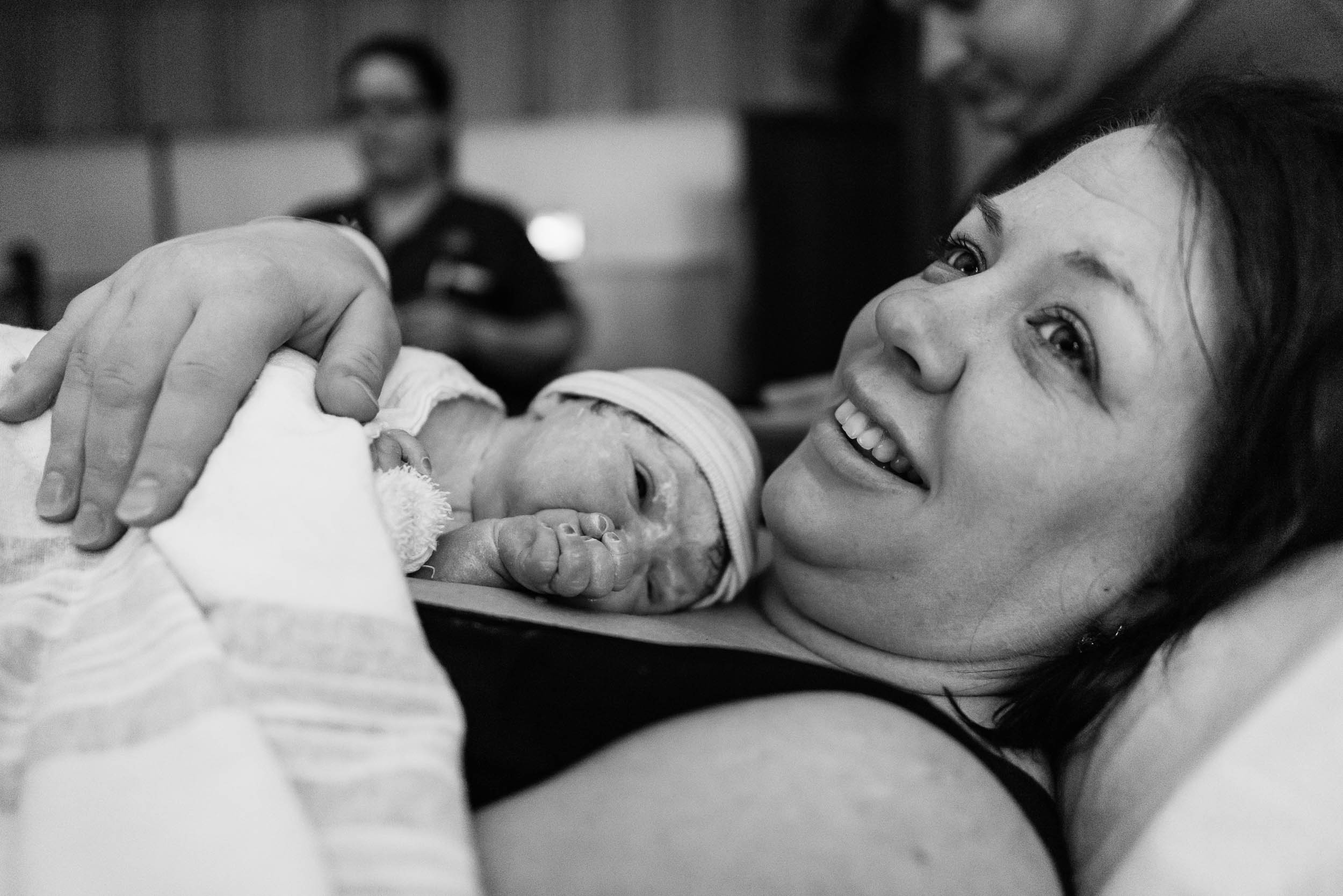 Woman holding her newborn baby in Northern Virginia hospital by Family Photographer Nicole Sanchez