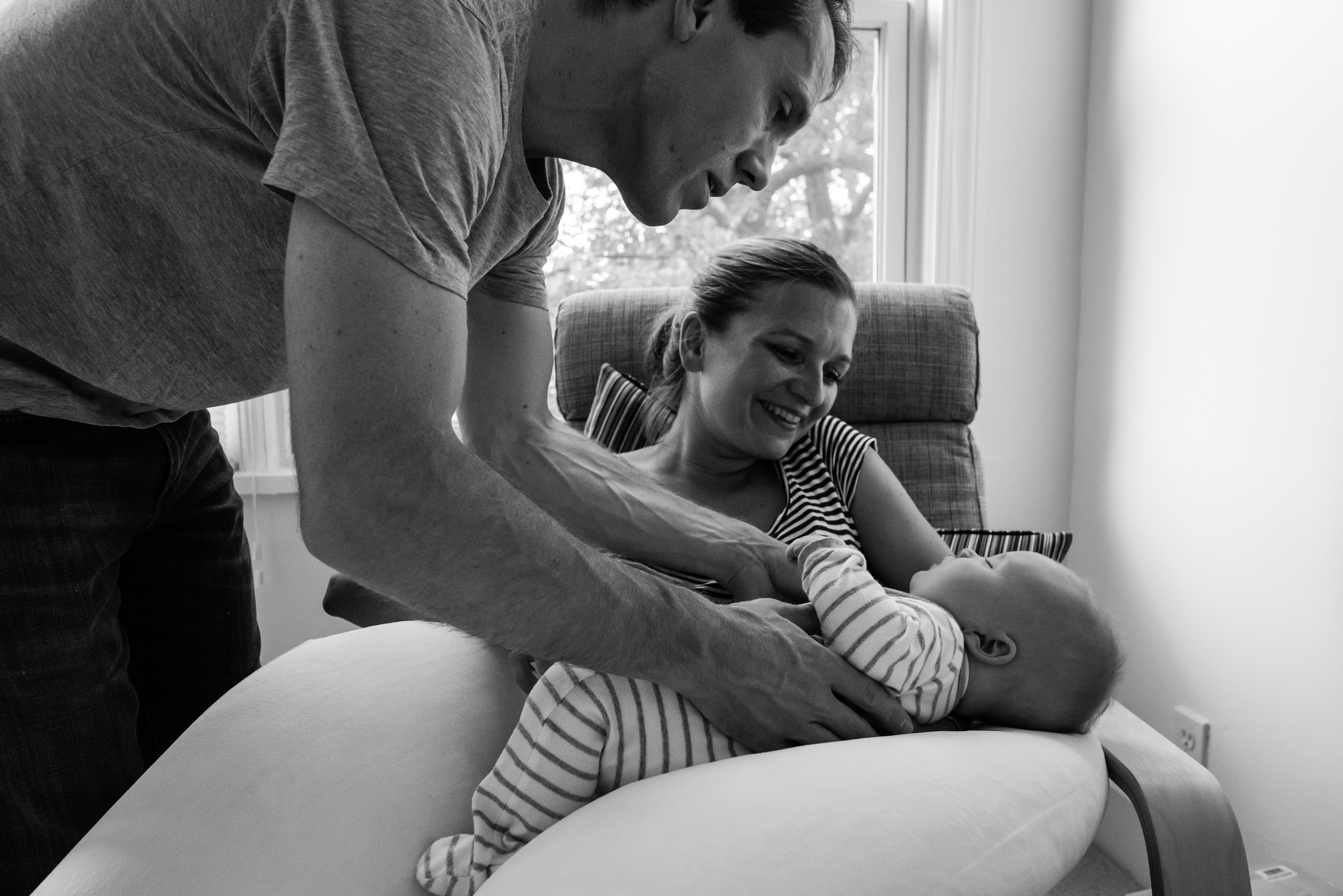 Dad picking up sleeping baby from Mom by Washington, DC Family Photographer Nicole Sanchez