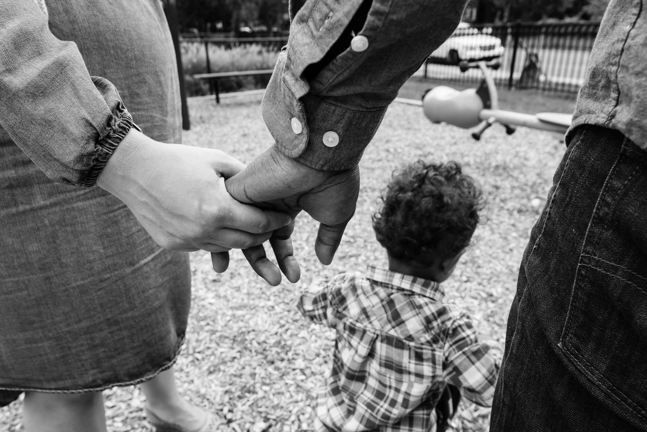 Mom and Dad holding hands while watching son play by Northern Virginia Family Photographer Nicole Sanchez