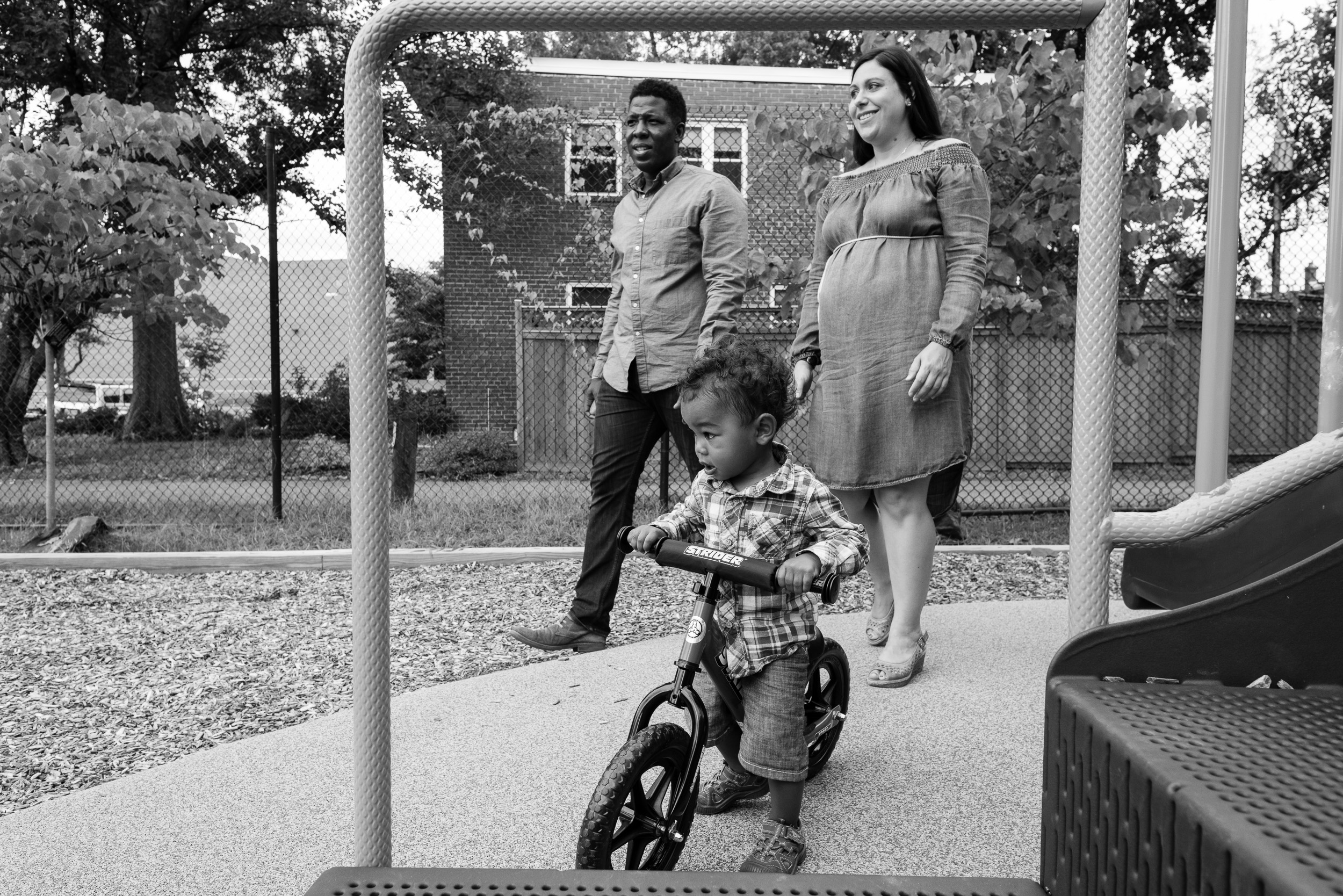 Toddler boy riding bike at playground with parents by Northern Virginia Family Photographer Nicole Sanchez