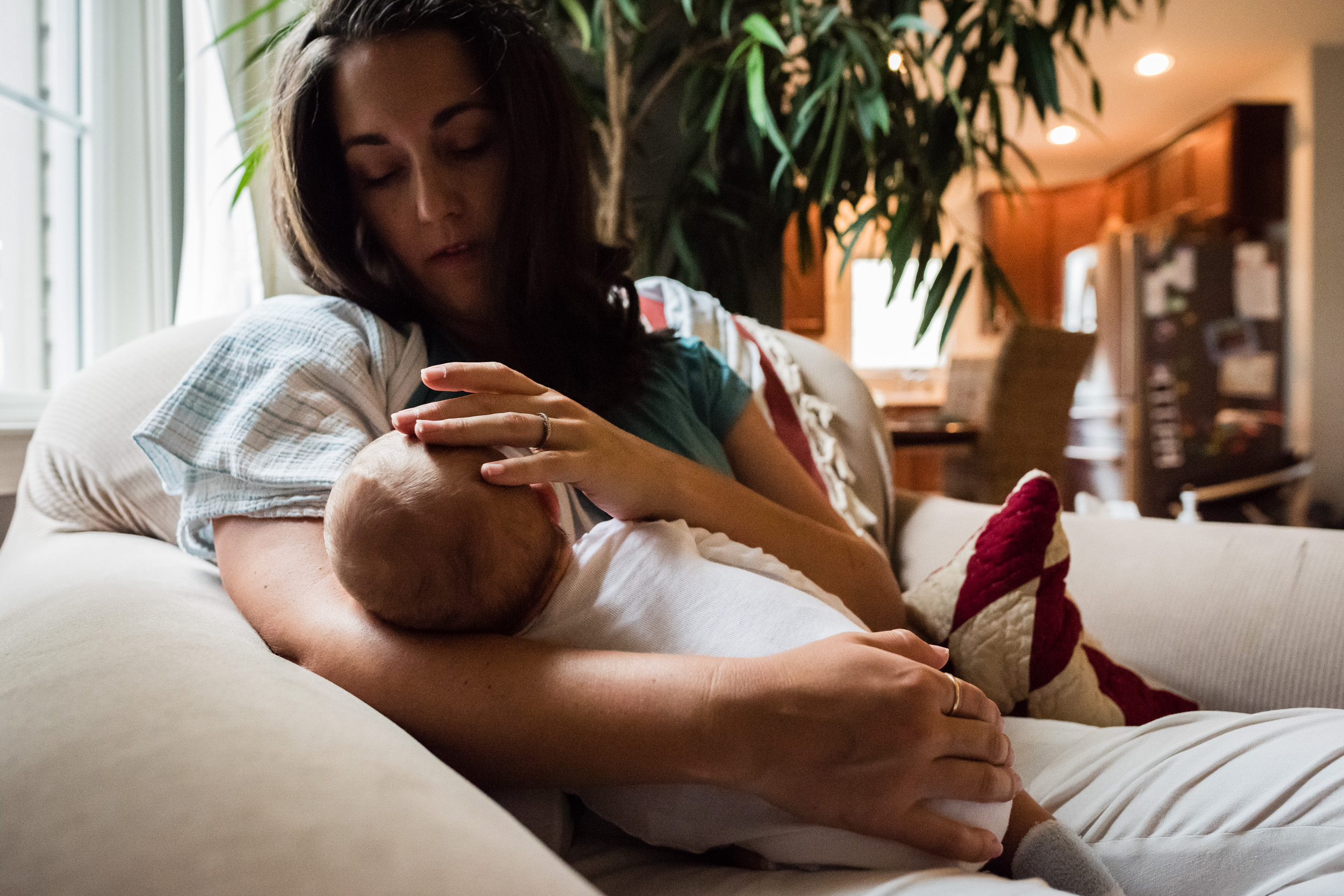 Mom cuddling nursing newborn at in-home family session in Northern Virginia by Family Photography Nicole Sanchez