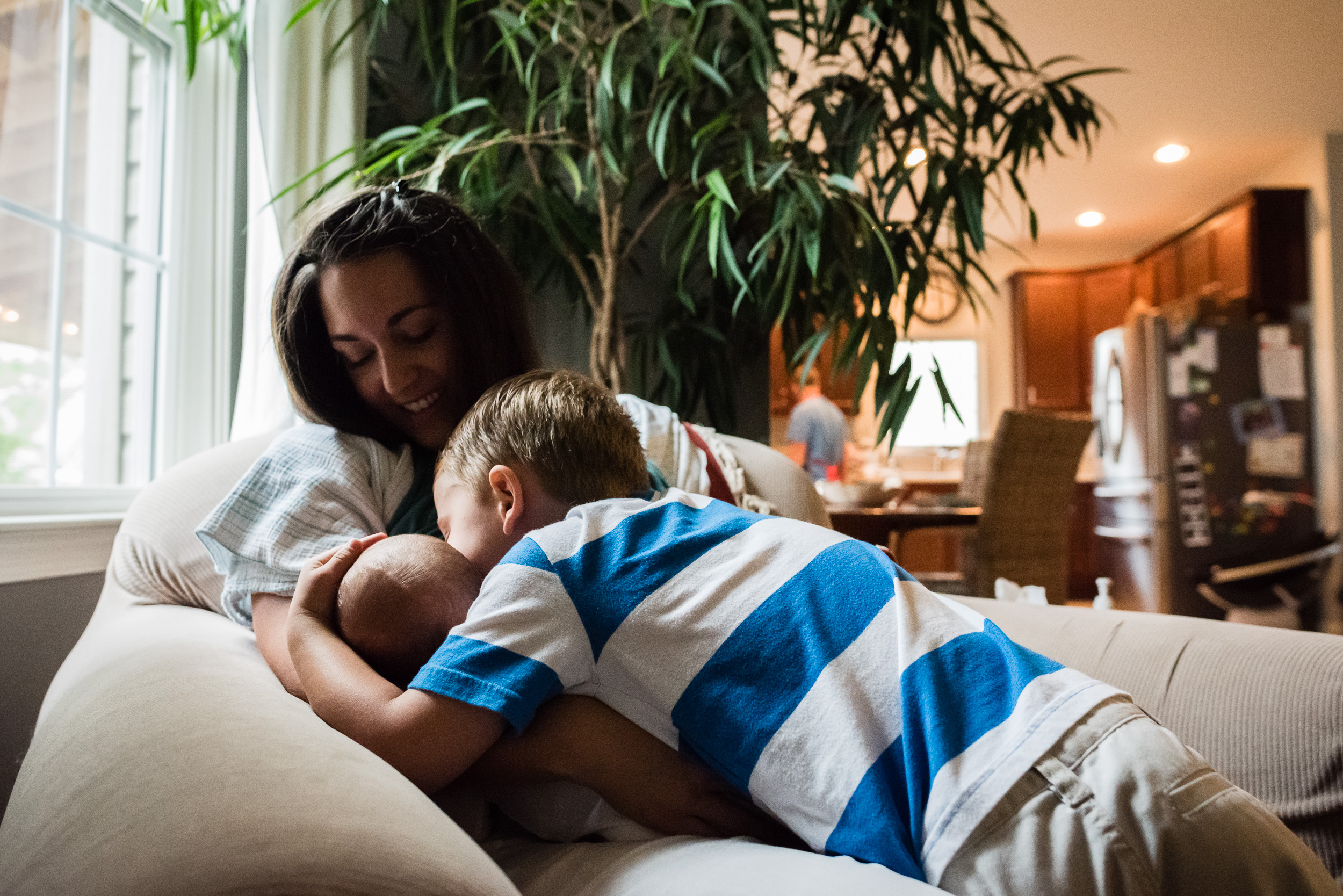 Big brother kissing newborn in at-home session in NOrthern Virginia by Family Photographer Nicole Sanchez