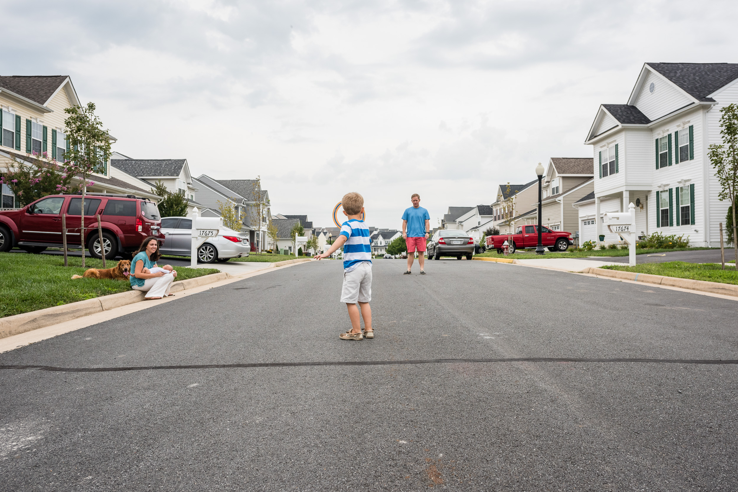 Father and son playing frisbee in street in Northern Virginia by Family Photographer Nicole Sanchez
