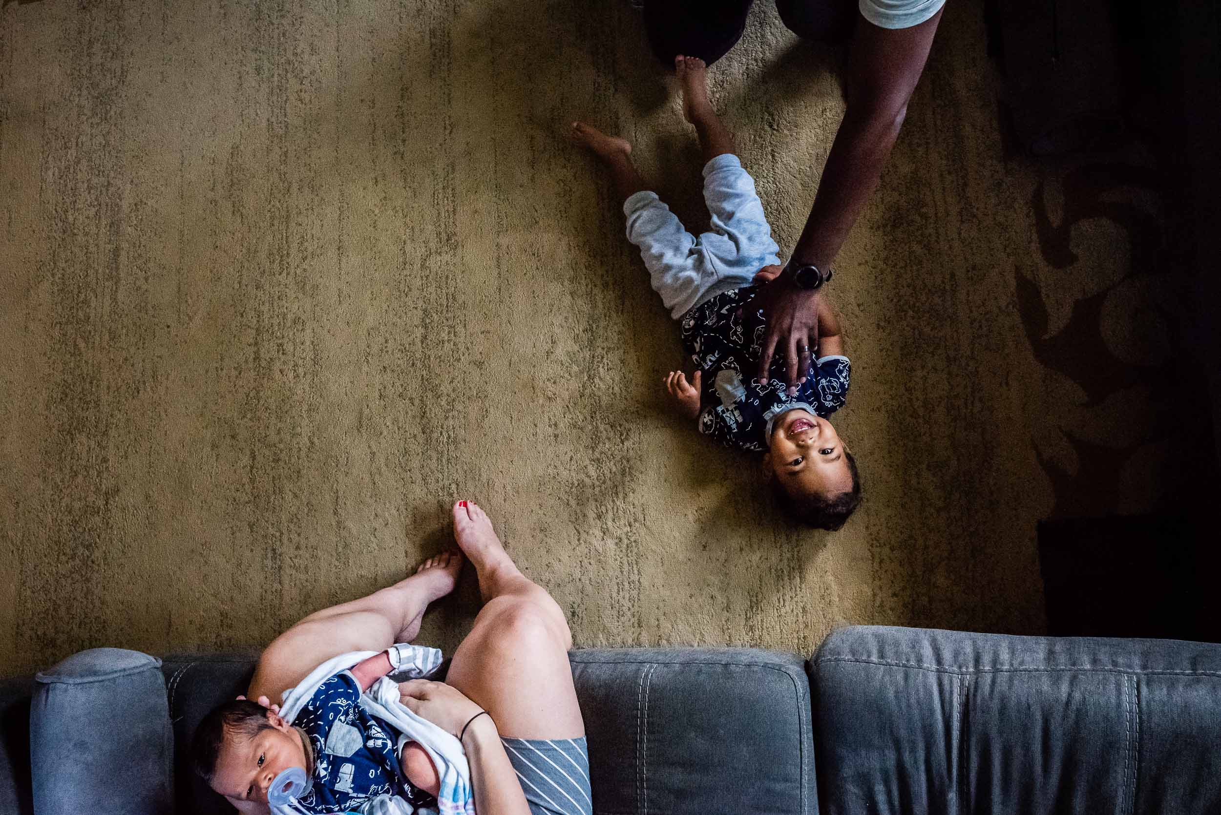 dad tickling toddler while mom watches with baby by family photographer nicole sanchez