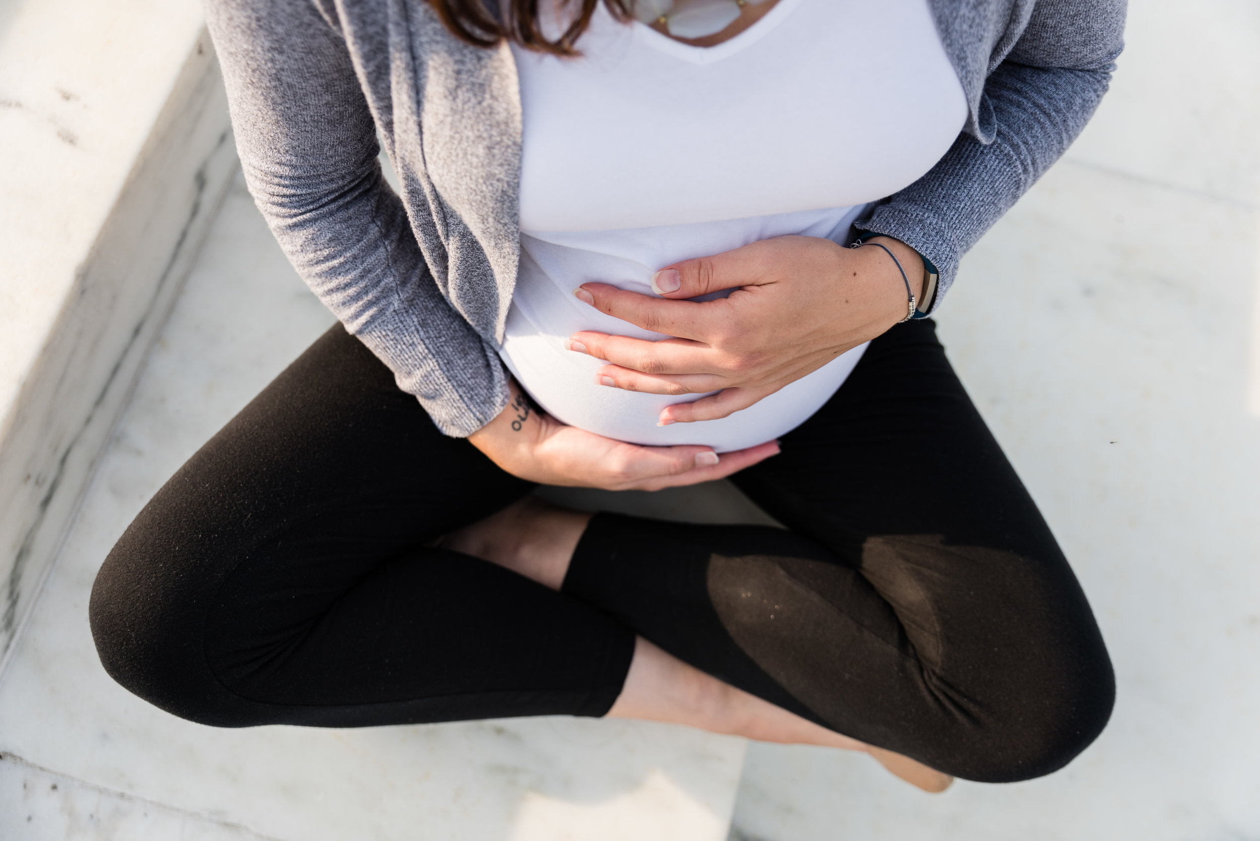 Mom holding pregnant belly on marble at U.S. Capitol Building in Washington, DC by Family Photographer Nicole Sanchez