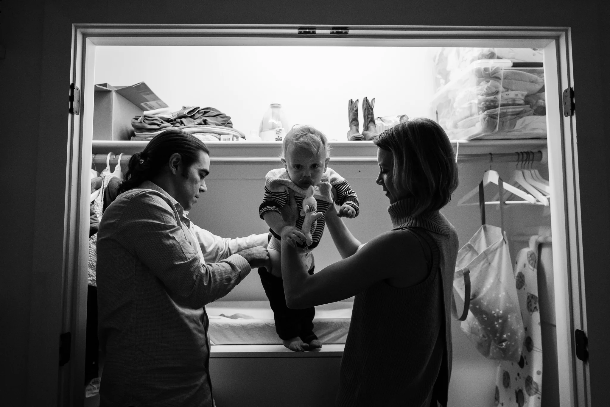 Parents putting pants on toddler boy in Washington, DC by Family Photographer Nicole Sanchez