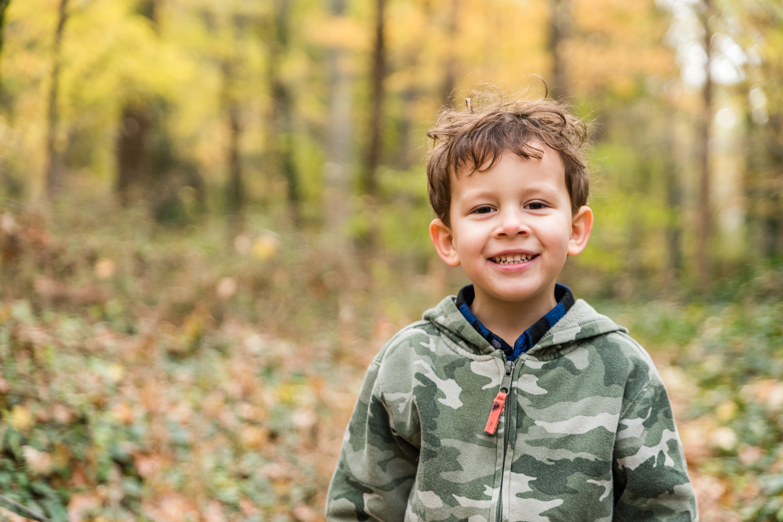 Boy smiling with fall leaves by Northern Virginia Family Photographer Nicole Sanchez