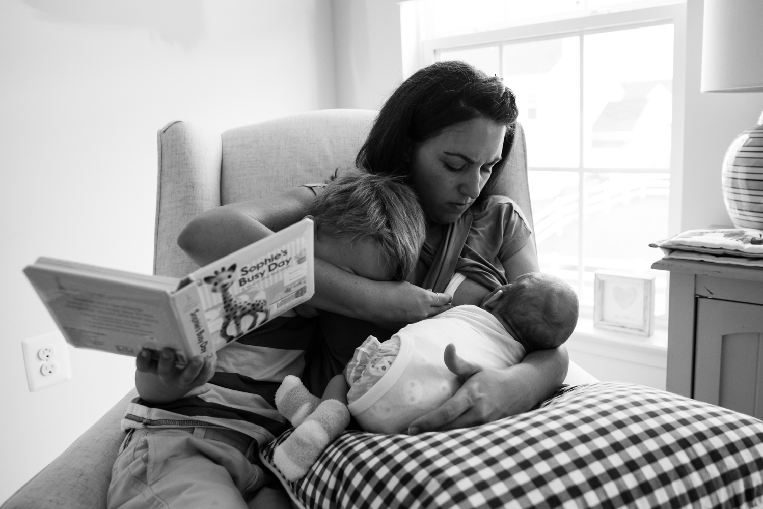 Mom trying to nurse newborn while reading to older son