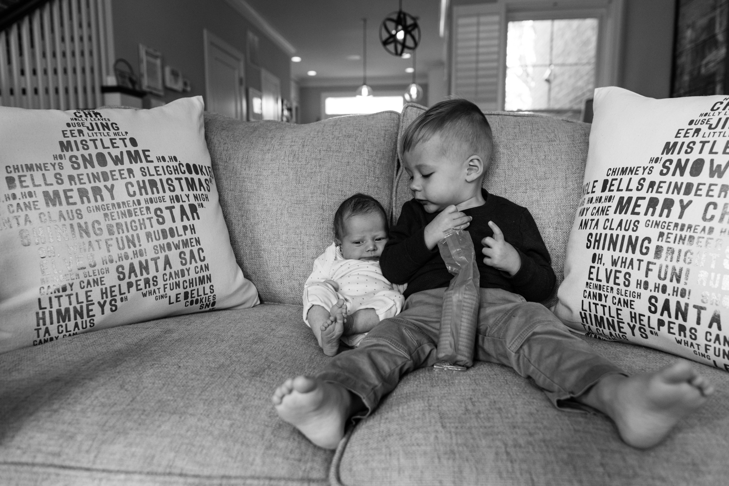 Boy looking at baby on couch while having a snack