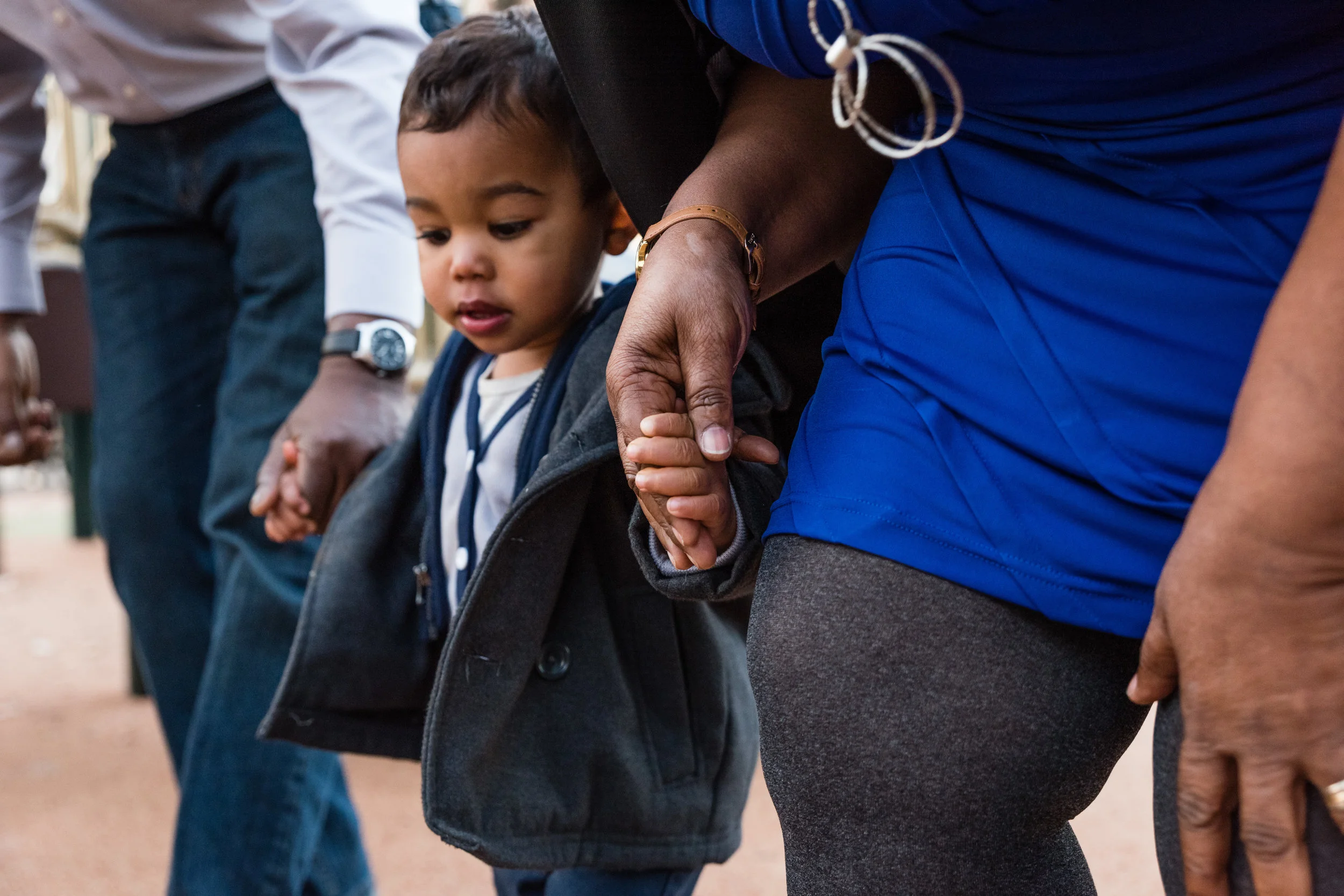 Toddler boy holding his grandparent's hands