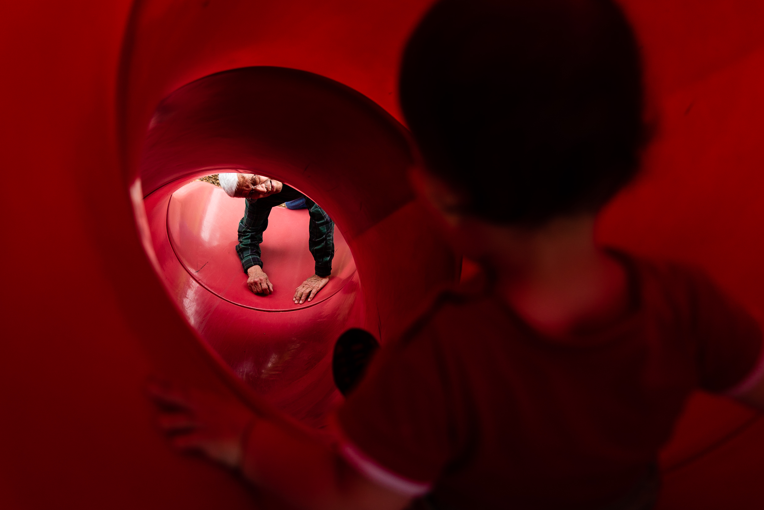 Grandfather waiting at bottom of tunnel slide by Northern Virginia Family Photographer Nicole Sanchez