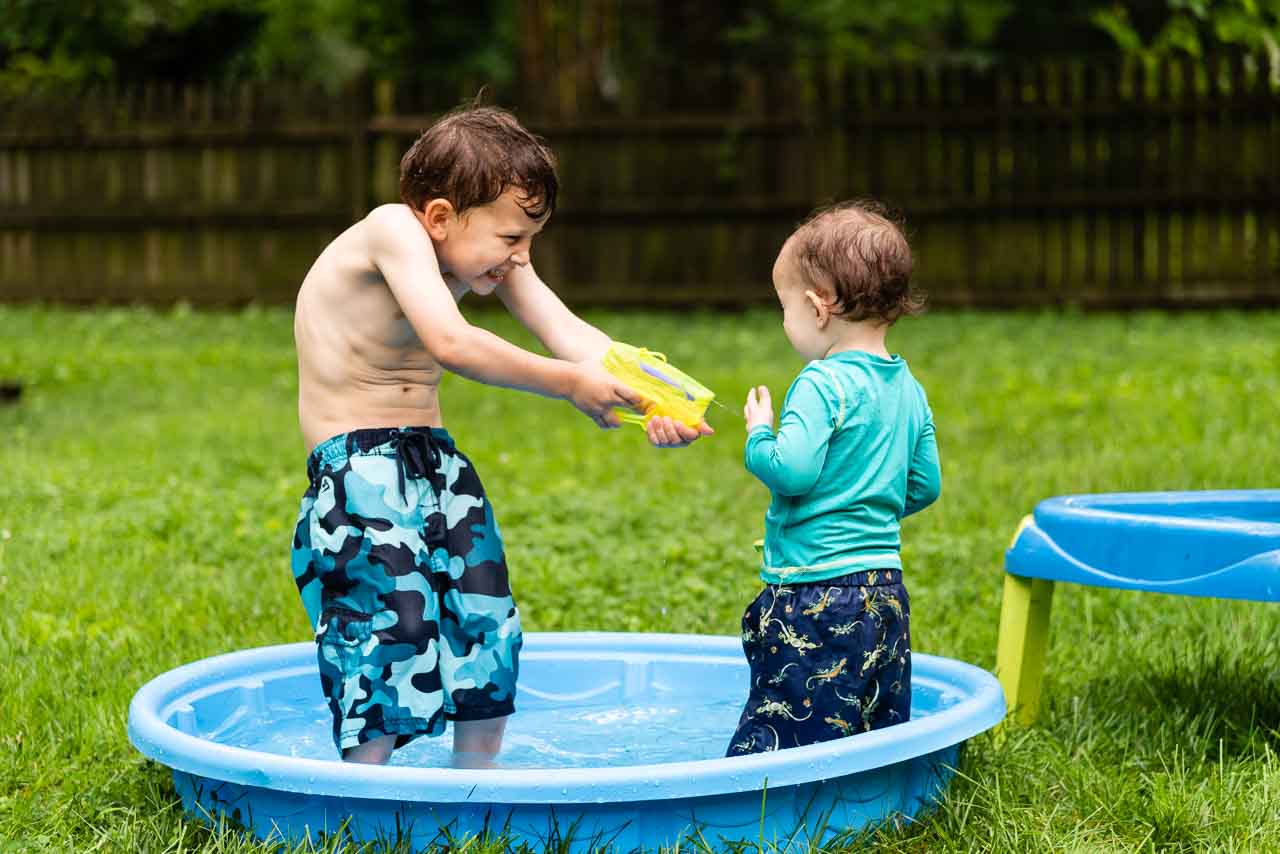 Big brother shooting toddler with water gun by Northern Virginia Family Photographer Nicole Sanchez