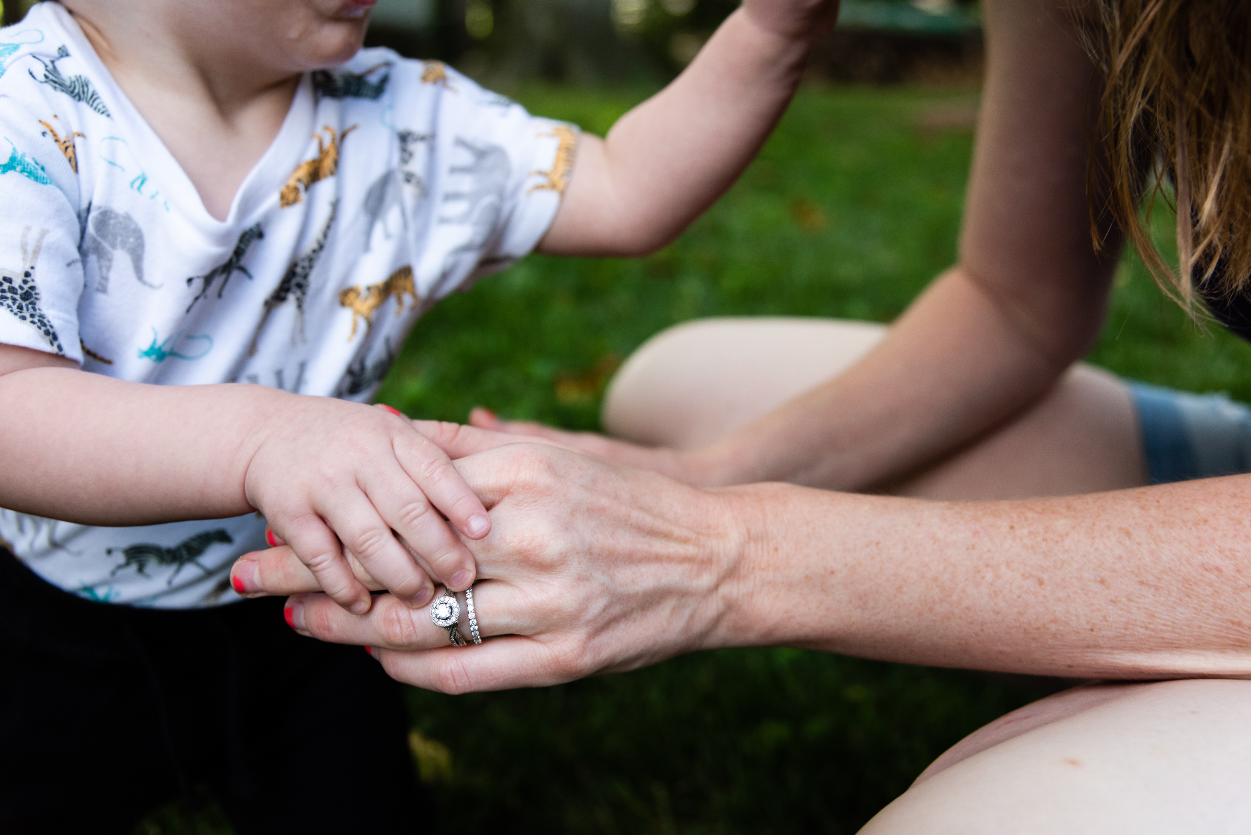 Toddler holding mom's hand in the backyard by northern virginia family photographer nicole sanchez