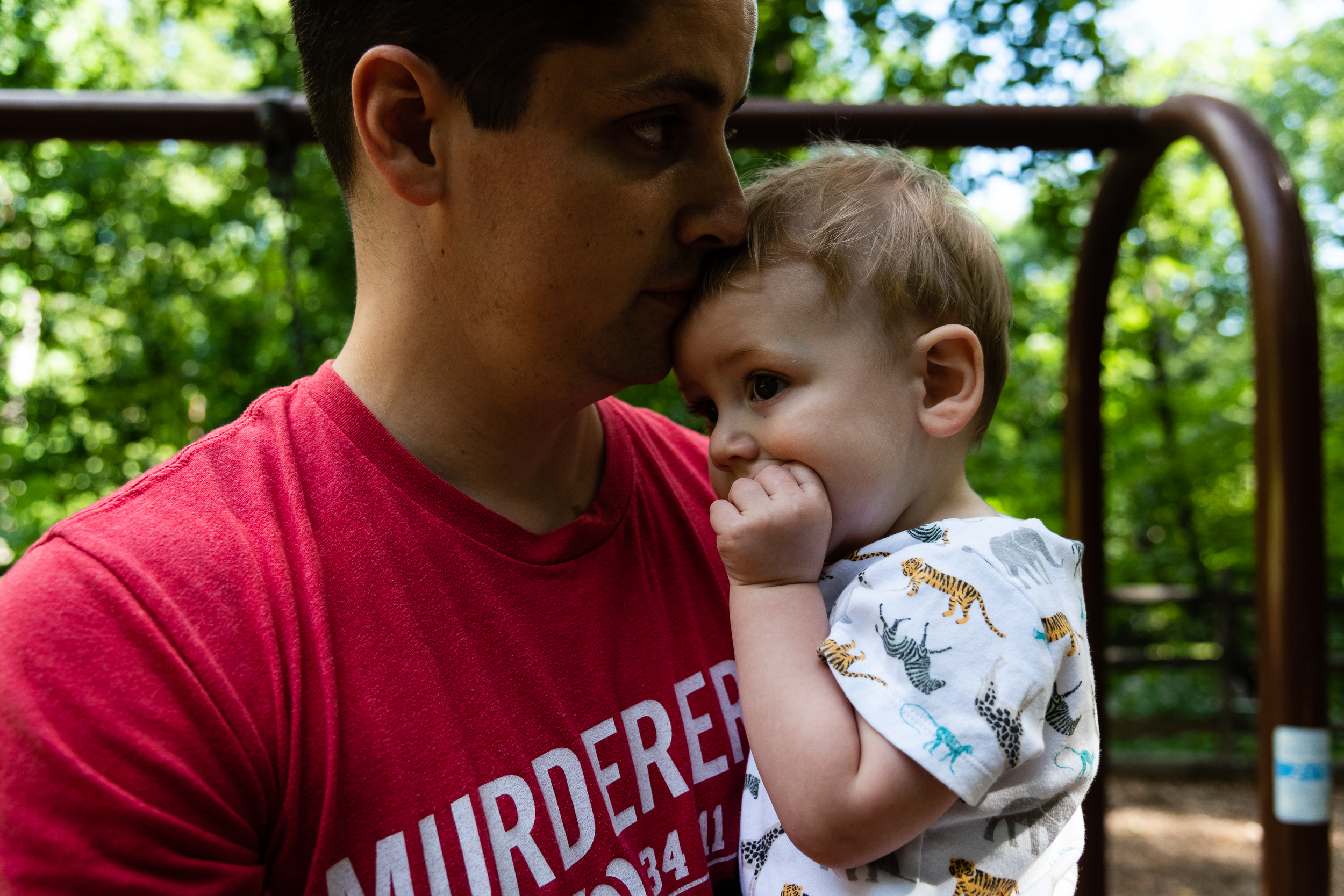 Dad kissing toddler son's head at park by northern virginia family photographer nicole sanchez