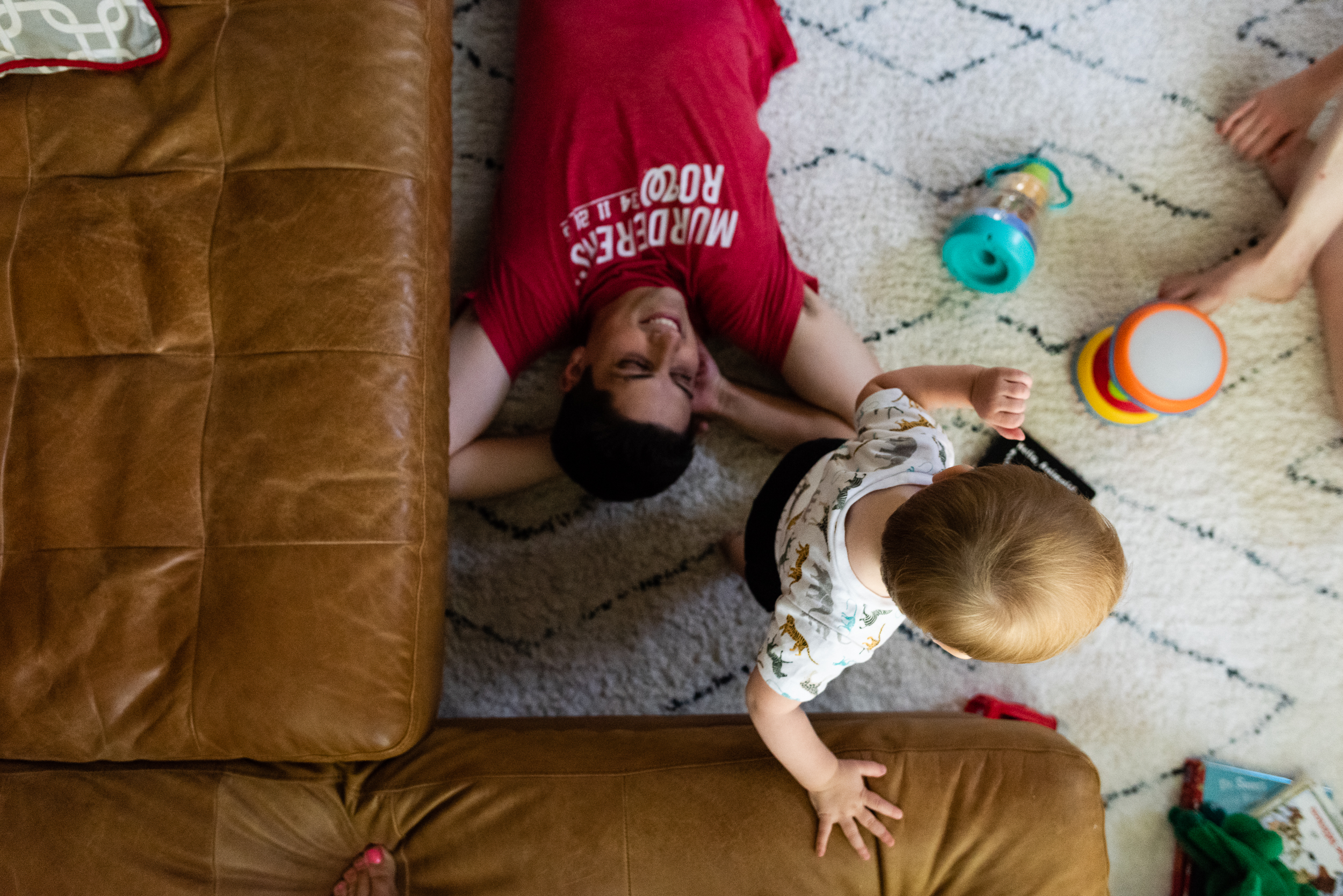 Dad laying on living room floor while toddler plays by northern virginia family photographer nicole sanchez