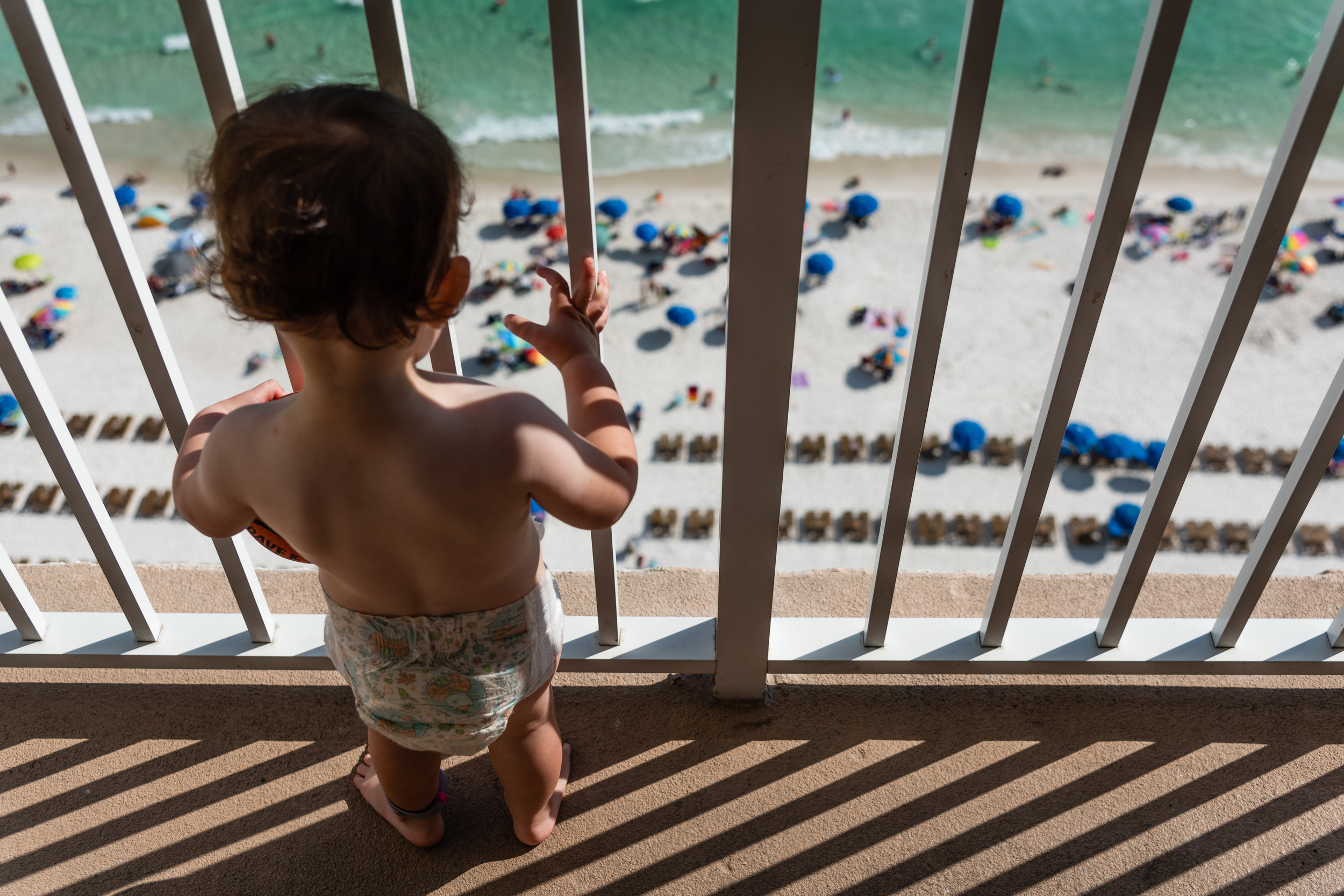 Toddler looking over balcony at beach by Northern Virginia Family Photographer Nicole Sanchez