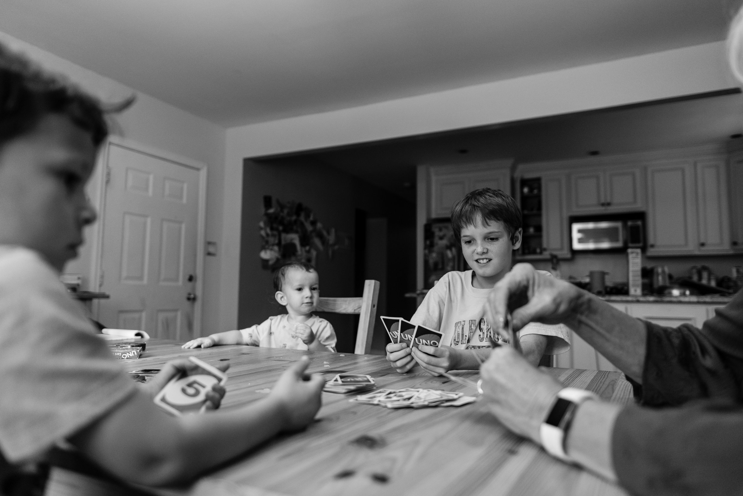 Family playing cards together at kitchen table by Northern Virginia Family Photographer Nicole Sanchez