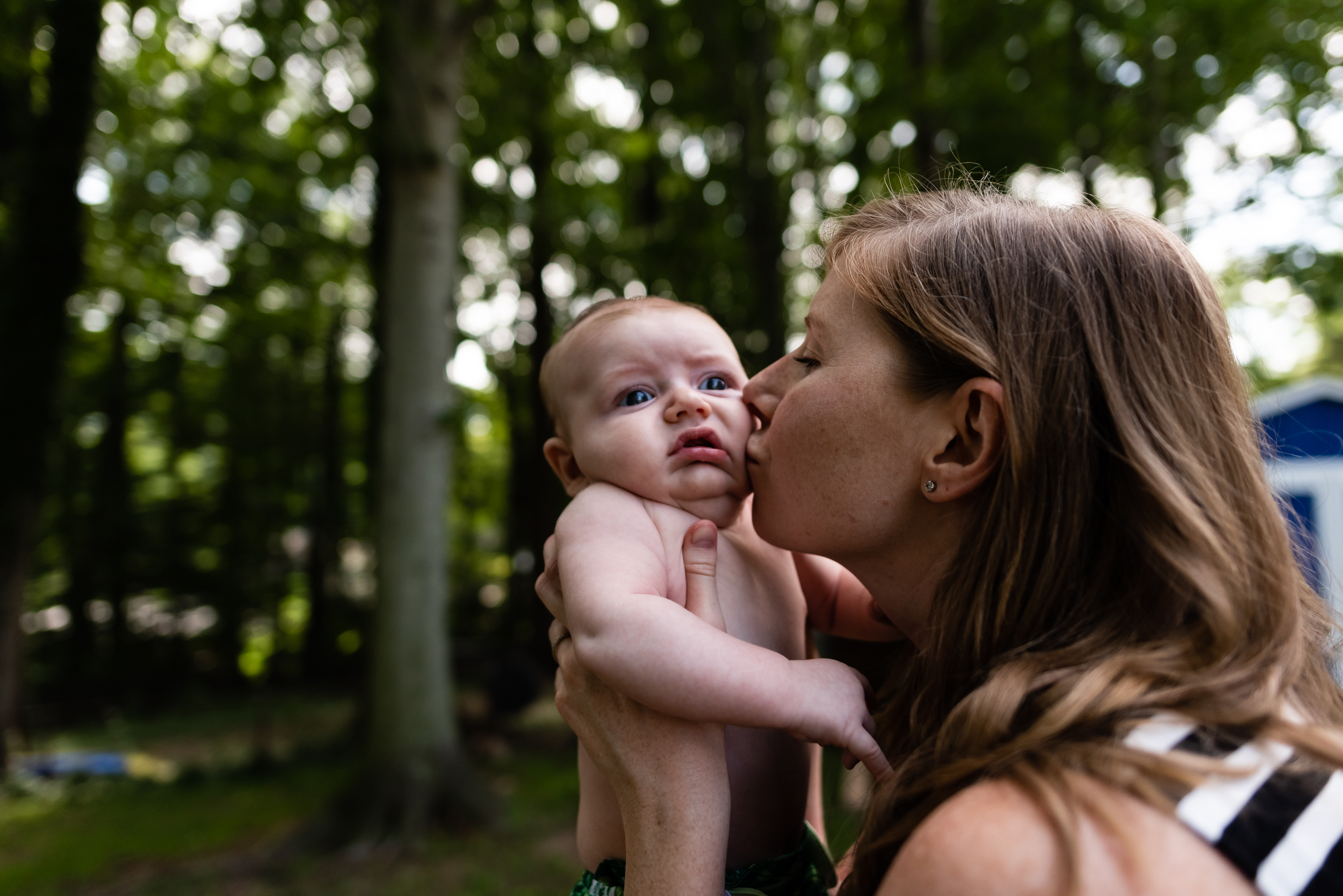 Mom kissing new baby outside by Northern Virginia Newborn Photographer Nicole Sanchez