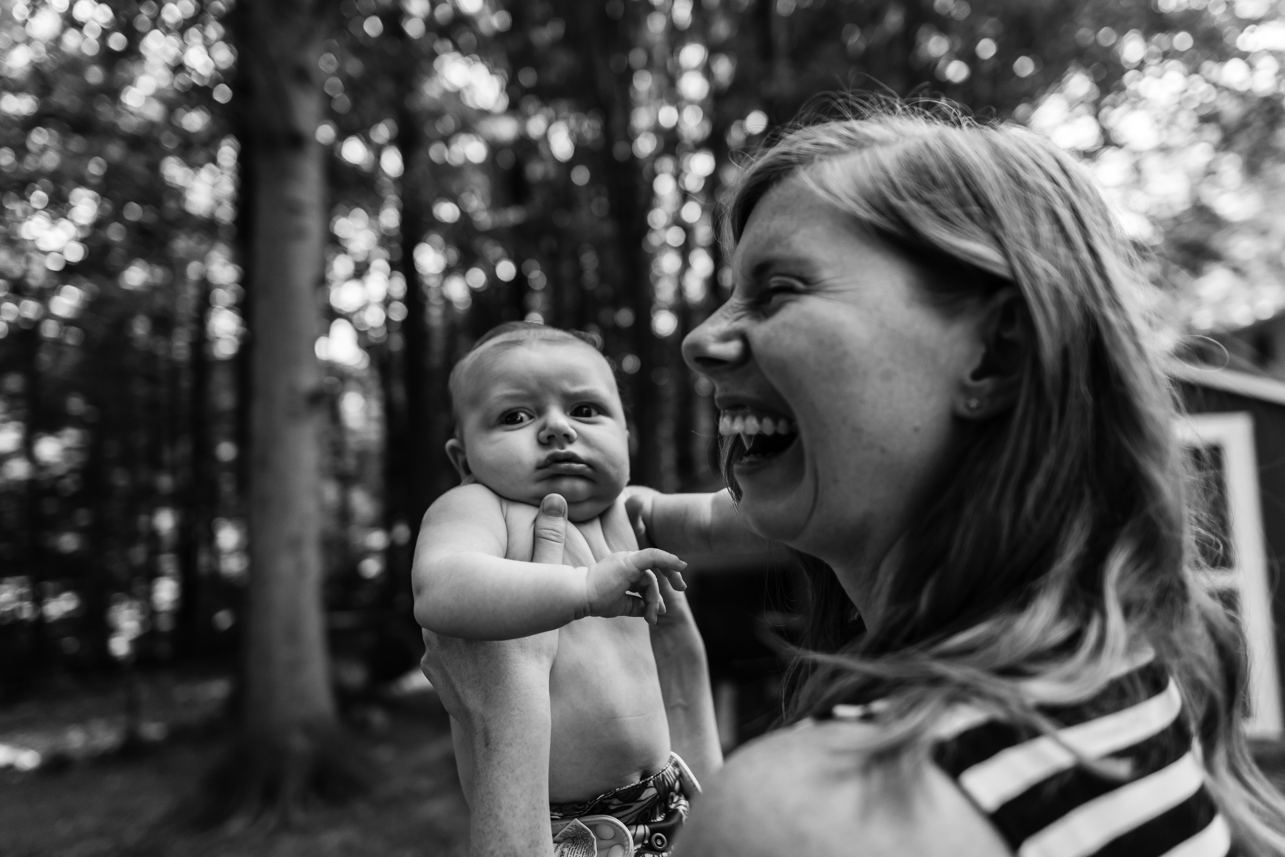 Mom laughing with new baby outside by Northern Virginia Newborn Photographer Nicole Sanchez