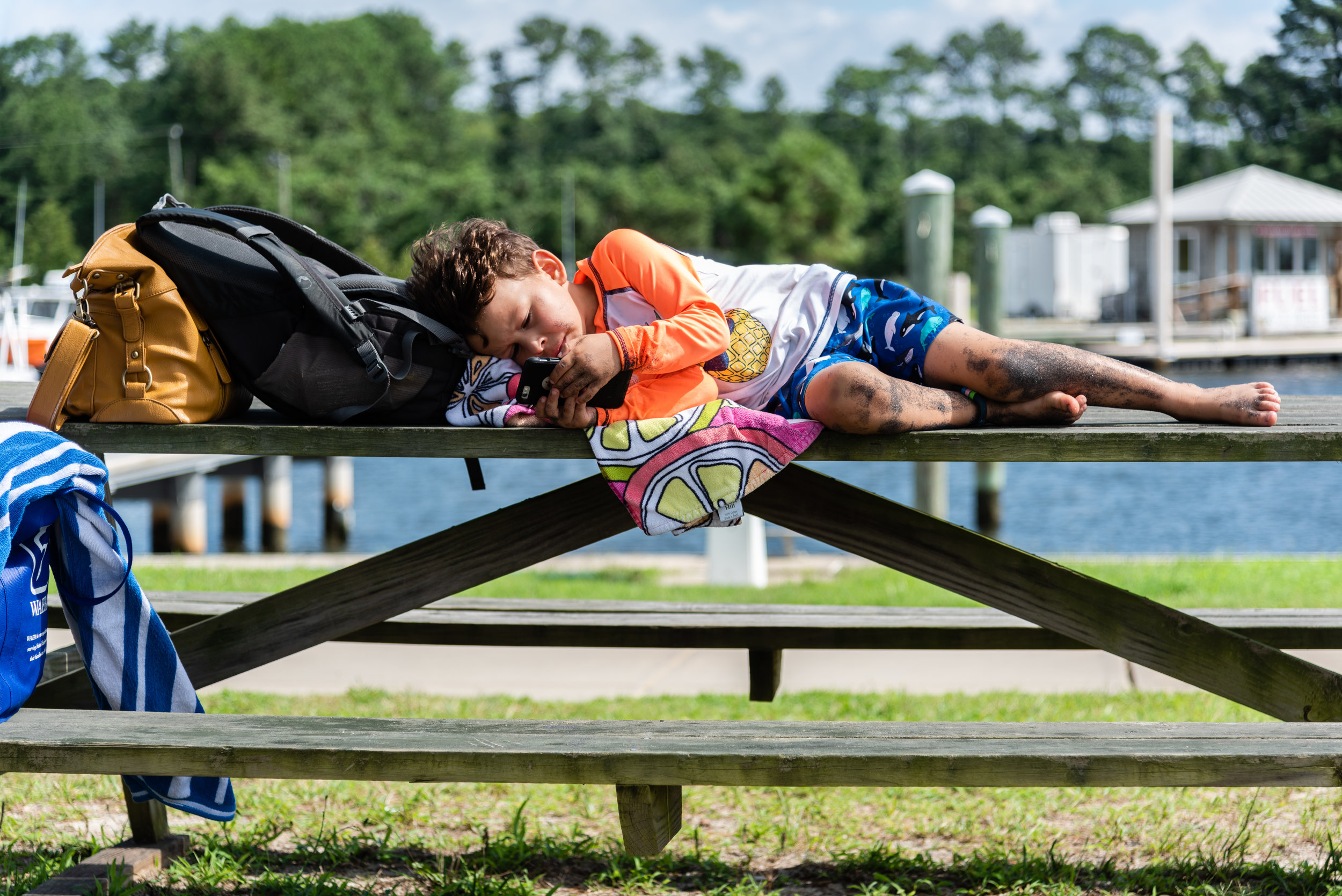 Boy laying on picnic table with iphone by Northern Virginia Family Photographer Nicole Sanchez