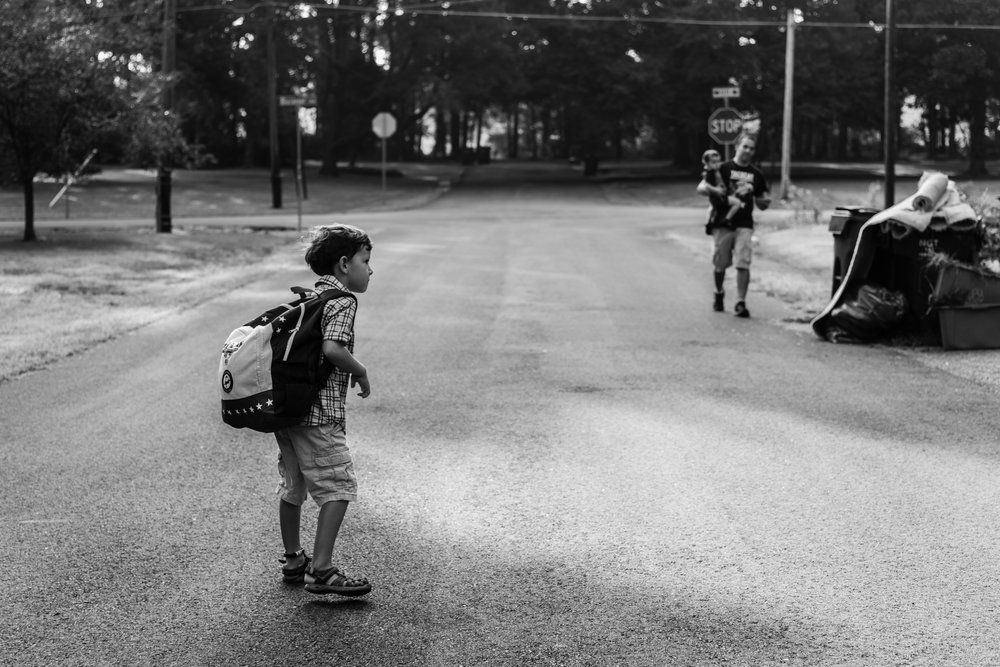 Boy with backpack waiting for dad and baby brother in Northern Virginia by Family Photographer Nicole Sanchez
