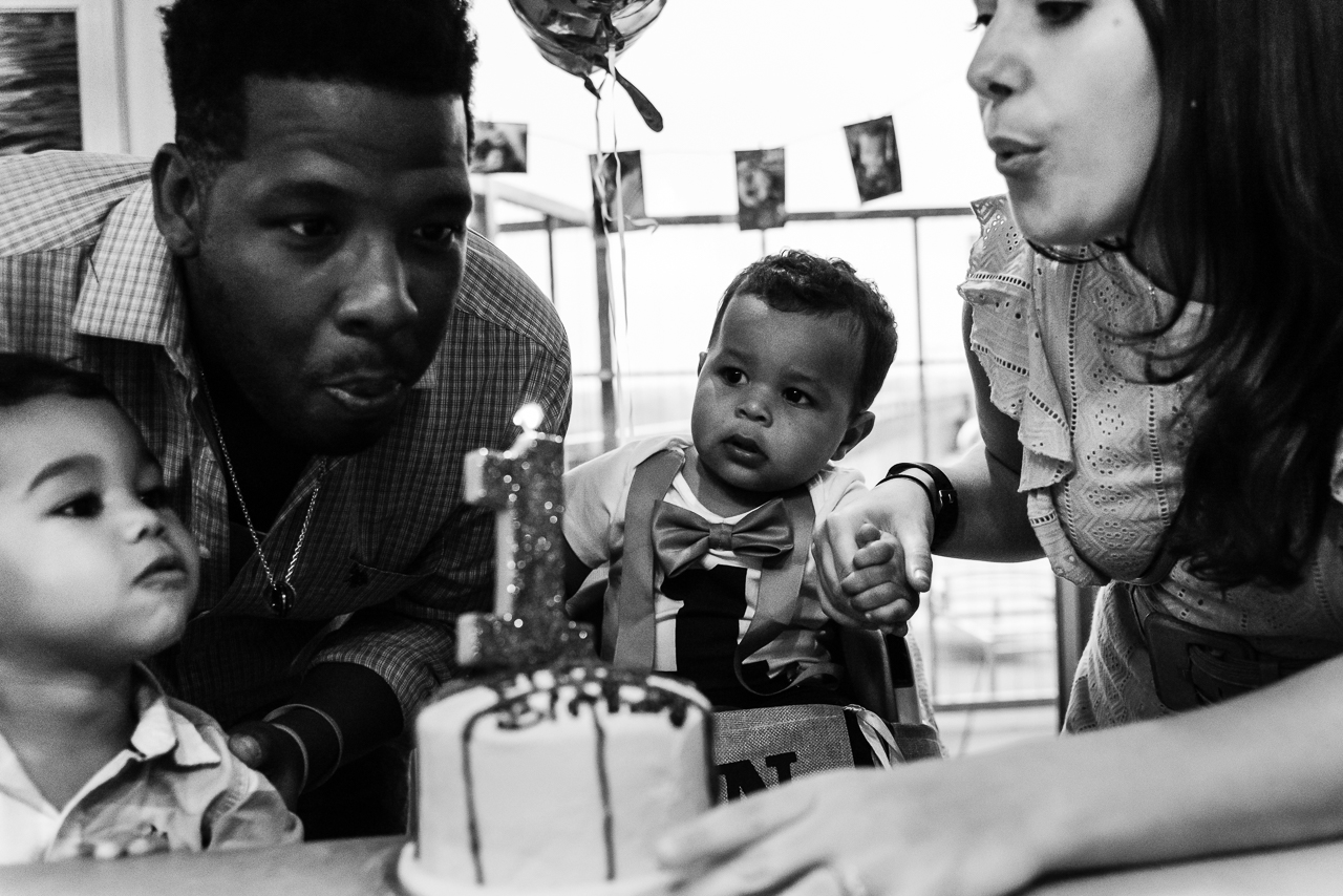 Mom dad and big brother helping baby blow out birthday candles by Northern Virginia Family Photographer Nicole Sanchez