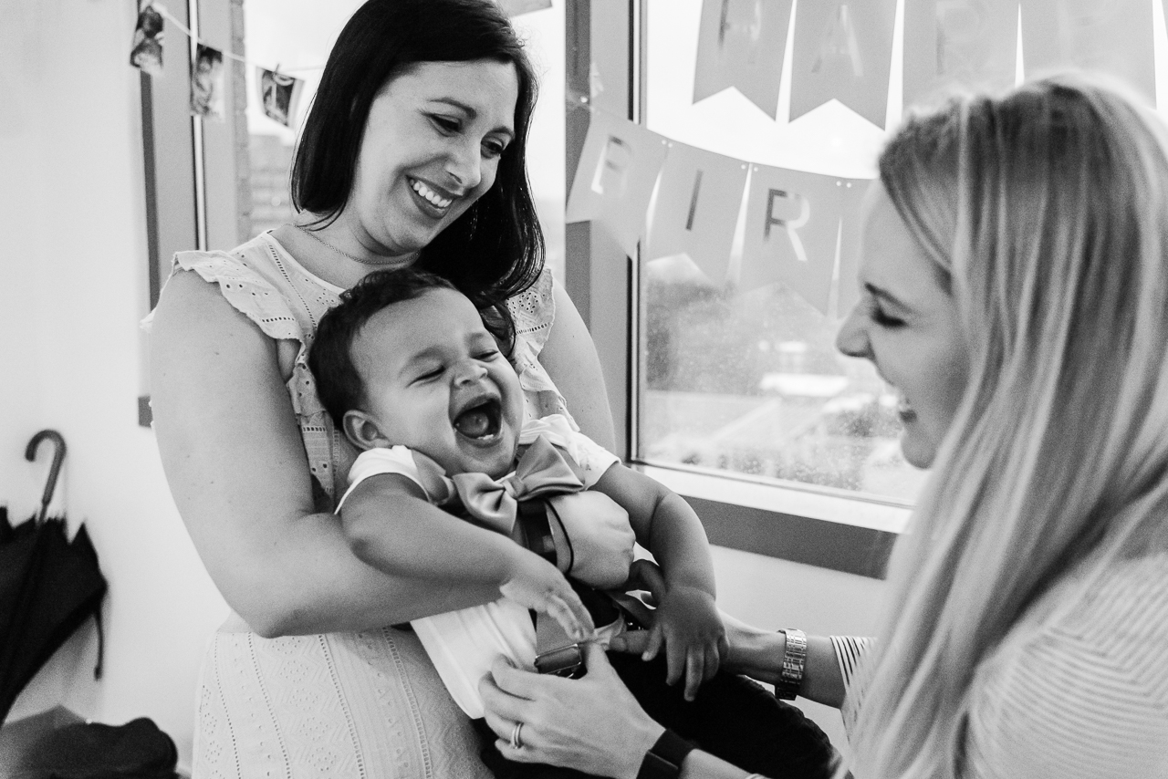 Mom holding laughing toddler at birthday party by Northern Virginia Family Photographer Nicole Sanchez