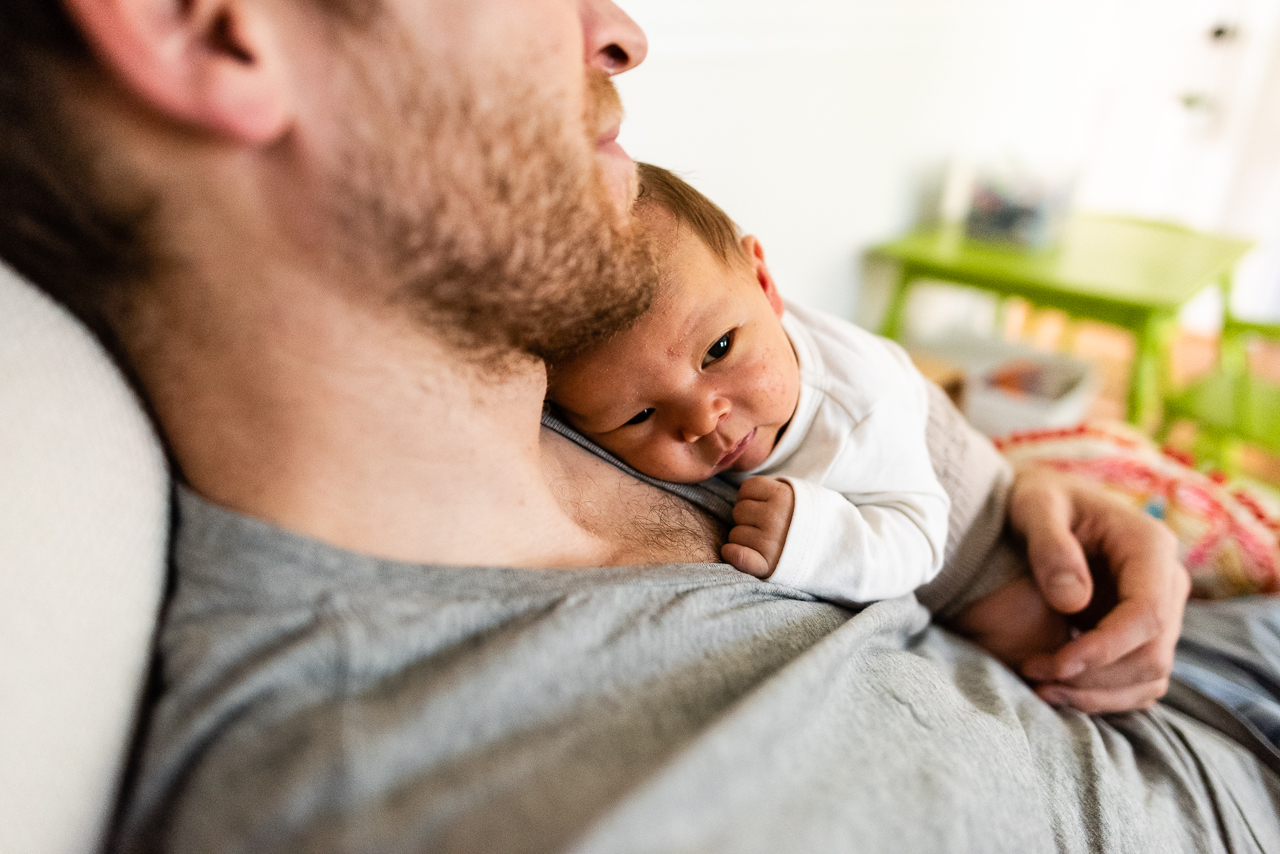 Father relaxing with newborn baby on his chest by Northern Virginia Family Photographer Nicole Sanchez