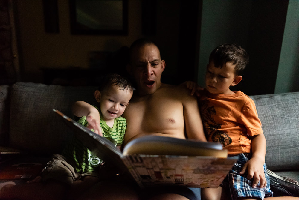 dad yawning while reading to two sons by Family Photographer Nicole Sanchez