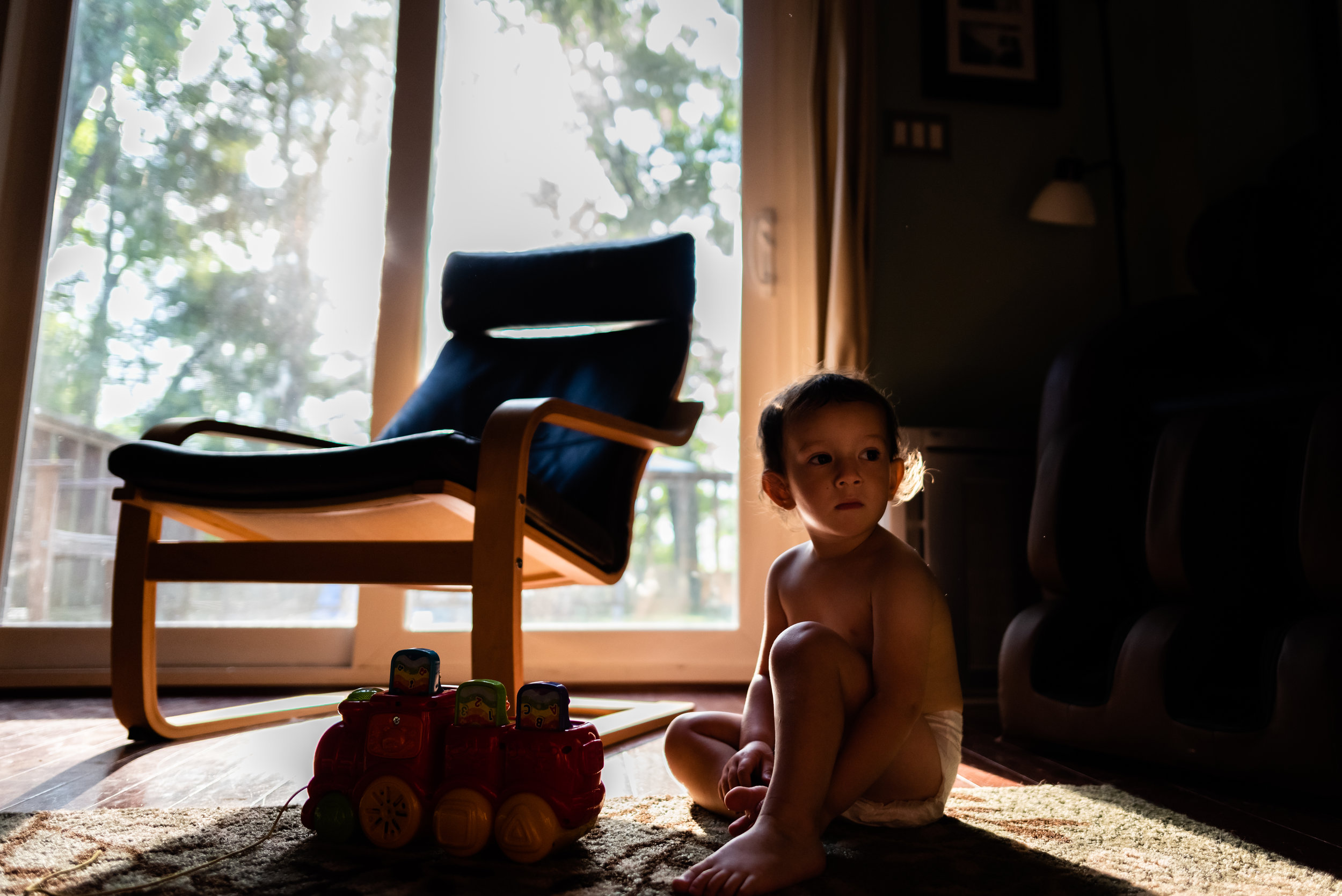 Little boy sitting on floor in pretty morning light by Family Photographer Nicole Sanchez