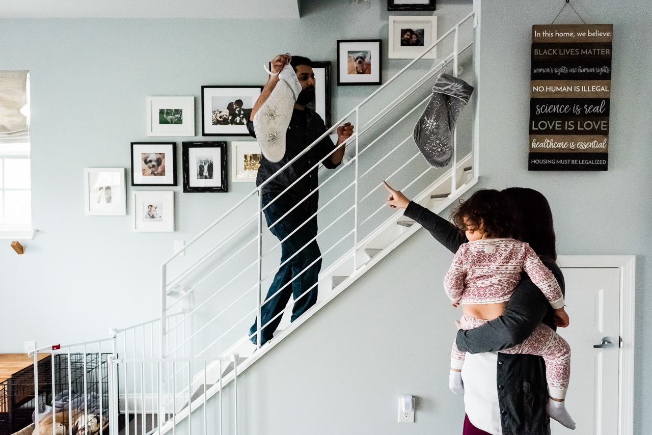 Dad hanging stocking on staircase with Mother and daughter