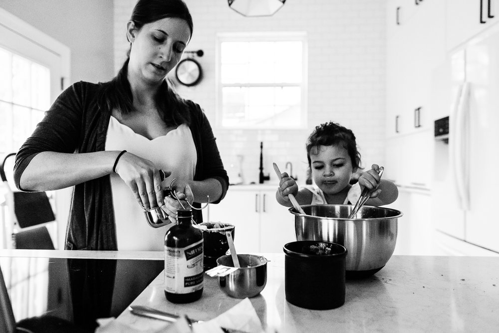 Little girl helping mom stir cookie dough