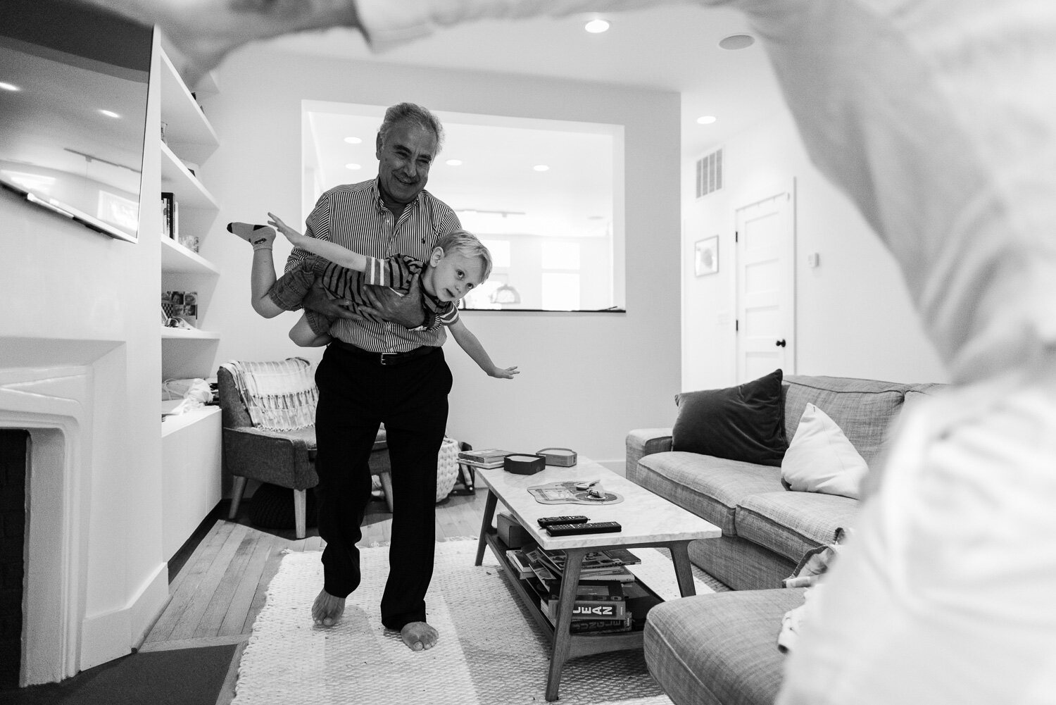 Grandfather flying grandson through living room by Northern Virginia Family Photographer Nicole Sanchez