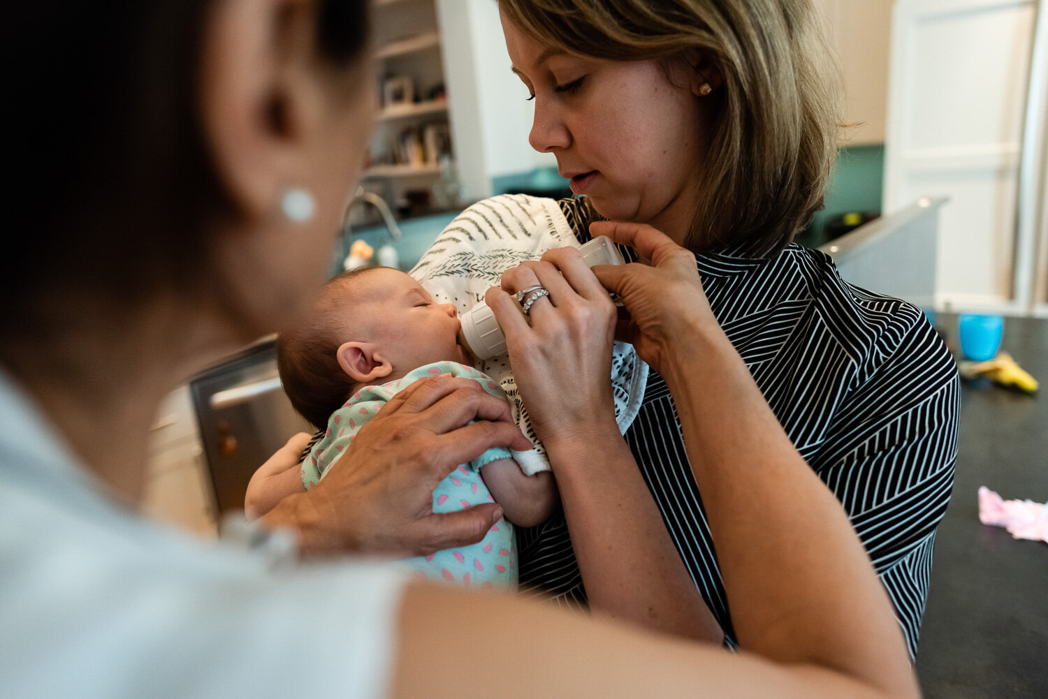 Grandmother helping mom bottle feed infant Northern Virginia Family Photographer Nicole Sanchez