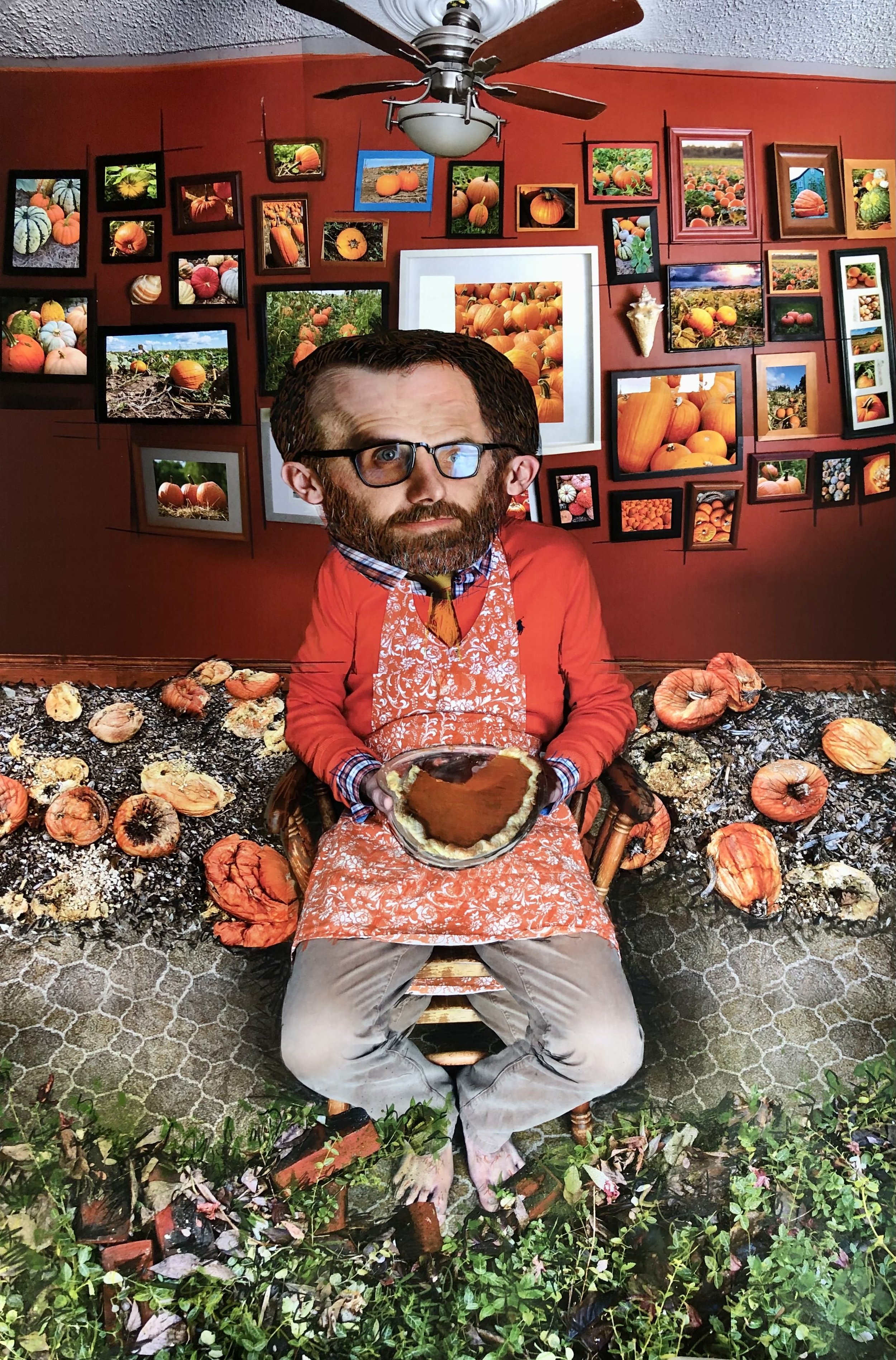   An image of Jason Bomers’ work, a photo collage of a man in an apron, holding a pumpkin pie. In the room he sits in, there’s a red wall filled with framed photos of pumpkins, he wears a red sweater vest, and his face is fragmented, with two images 