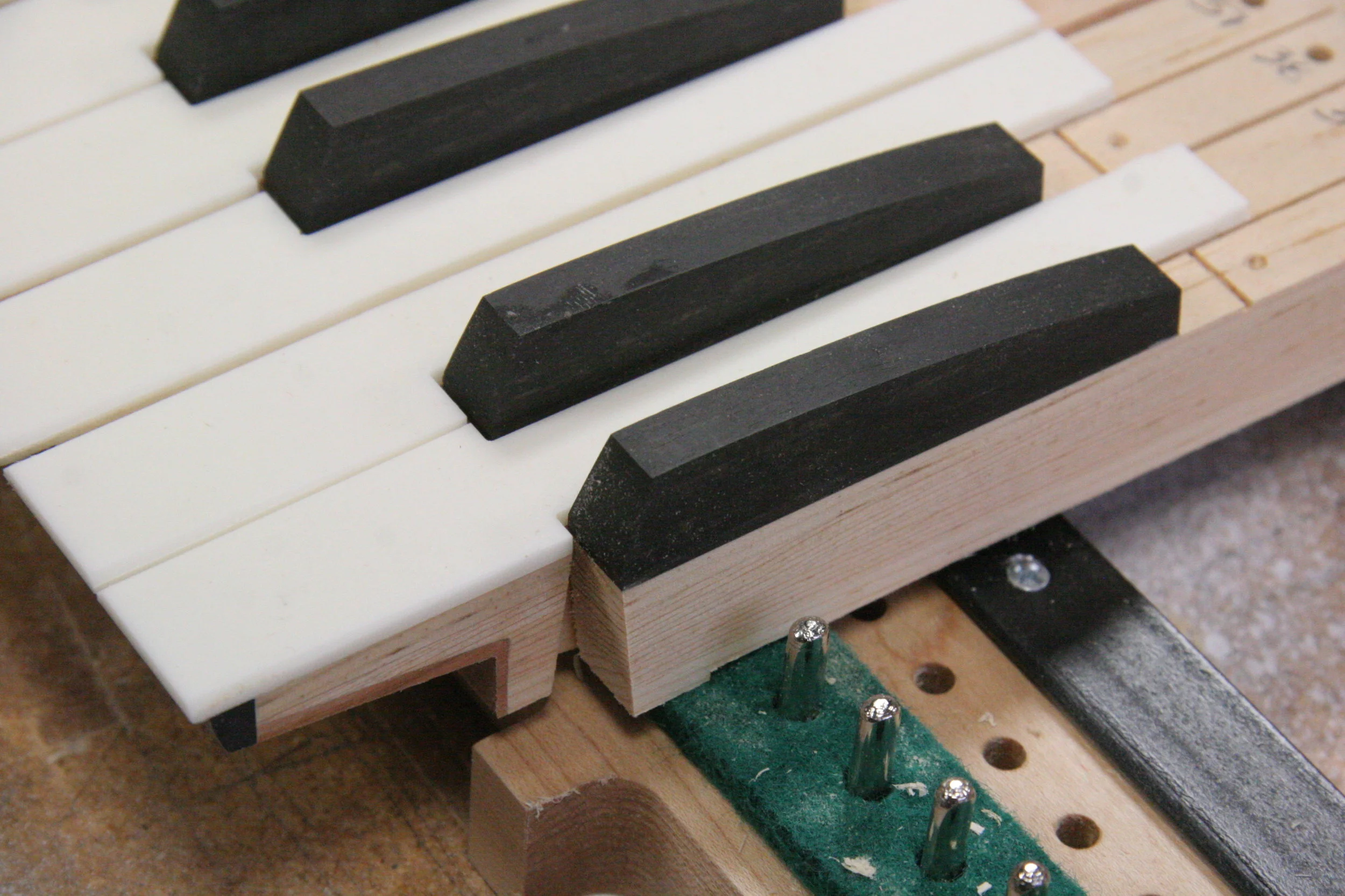 Construction detail showing cherry and ebony covers on key under-cut and sharps of ebony.