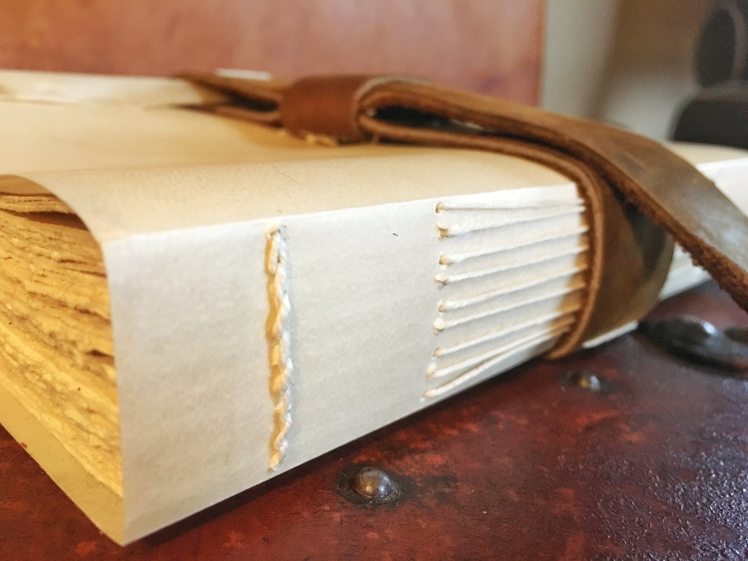 Simple long-stitch sewing on a closed spine of vellum.