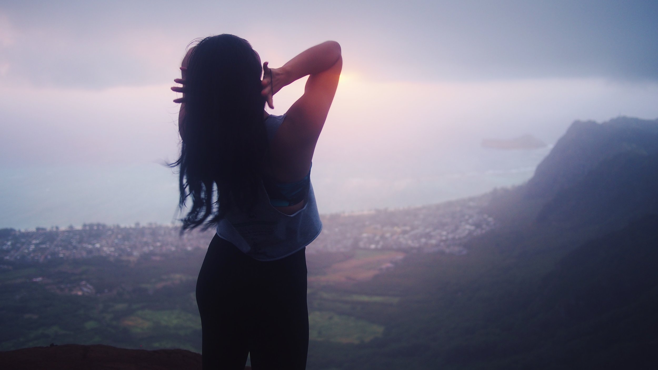 Sillhouette of a girl on a mountain at sunrise